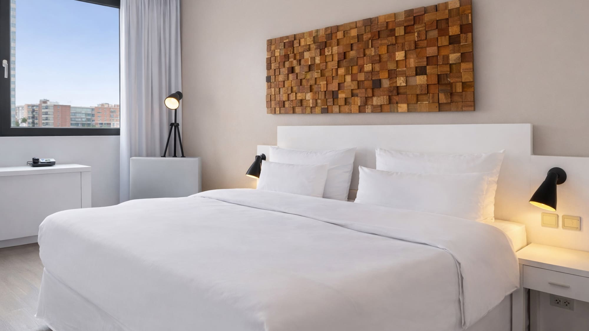 a bed with white sheets and pillows in a room with a lamp and a window