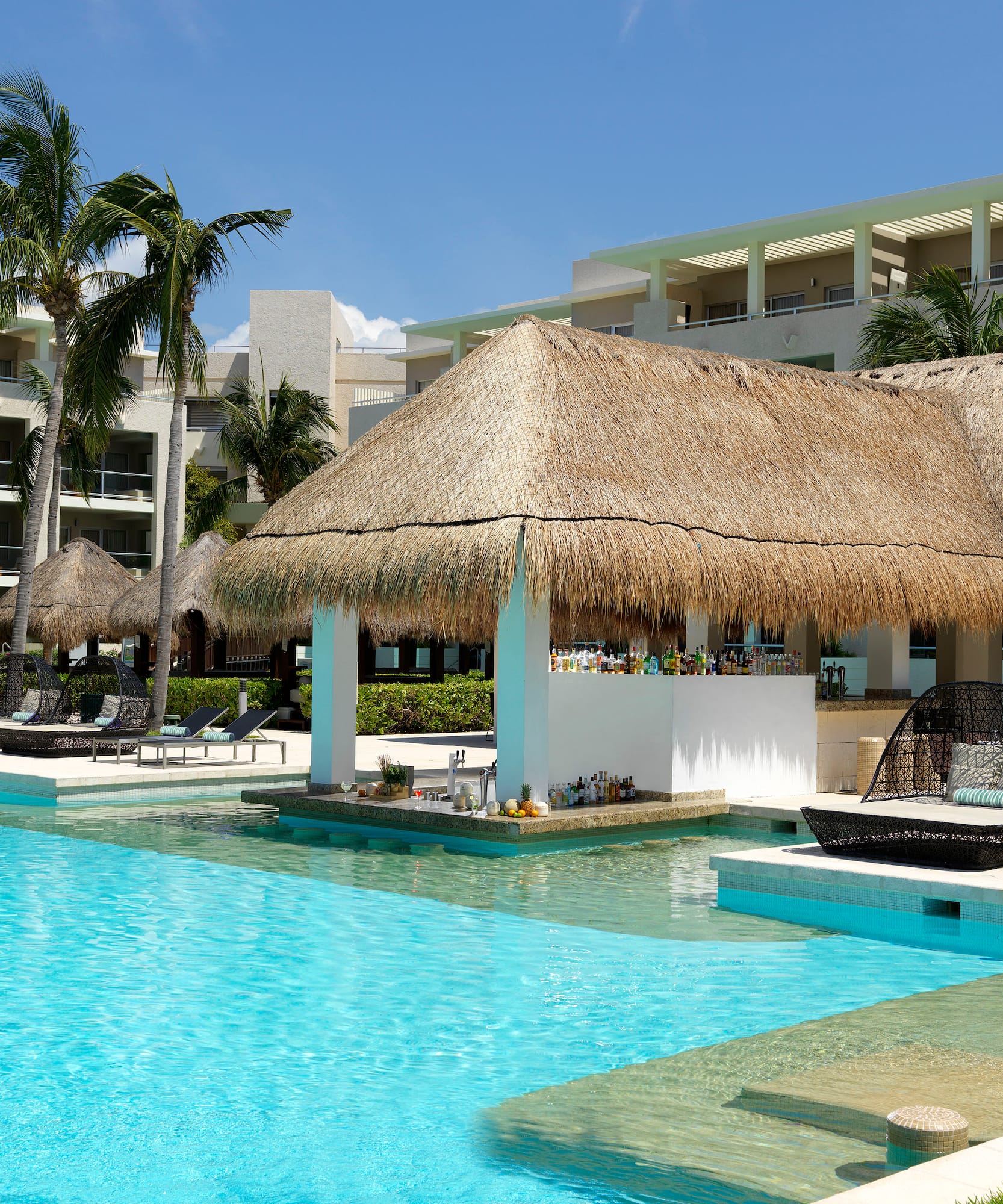 a pool with a thatched roof and lounge chairs