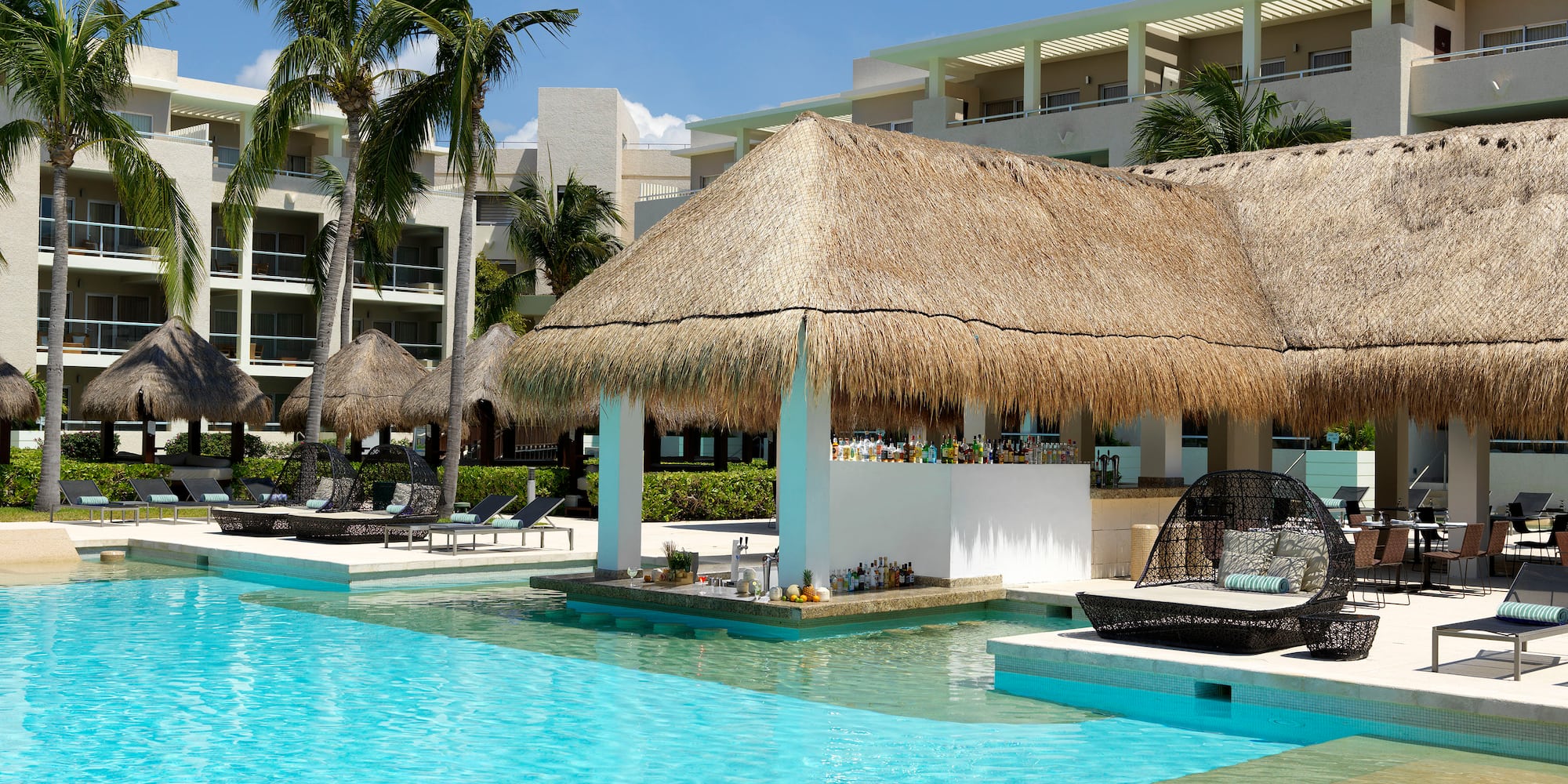 a pool with a thatched roof and lounge chairs