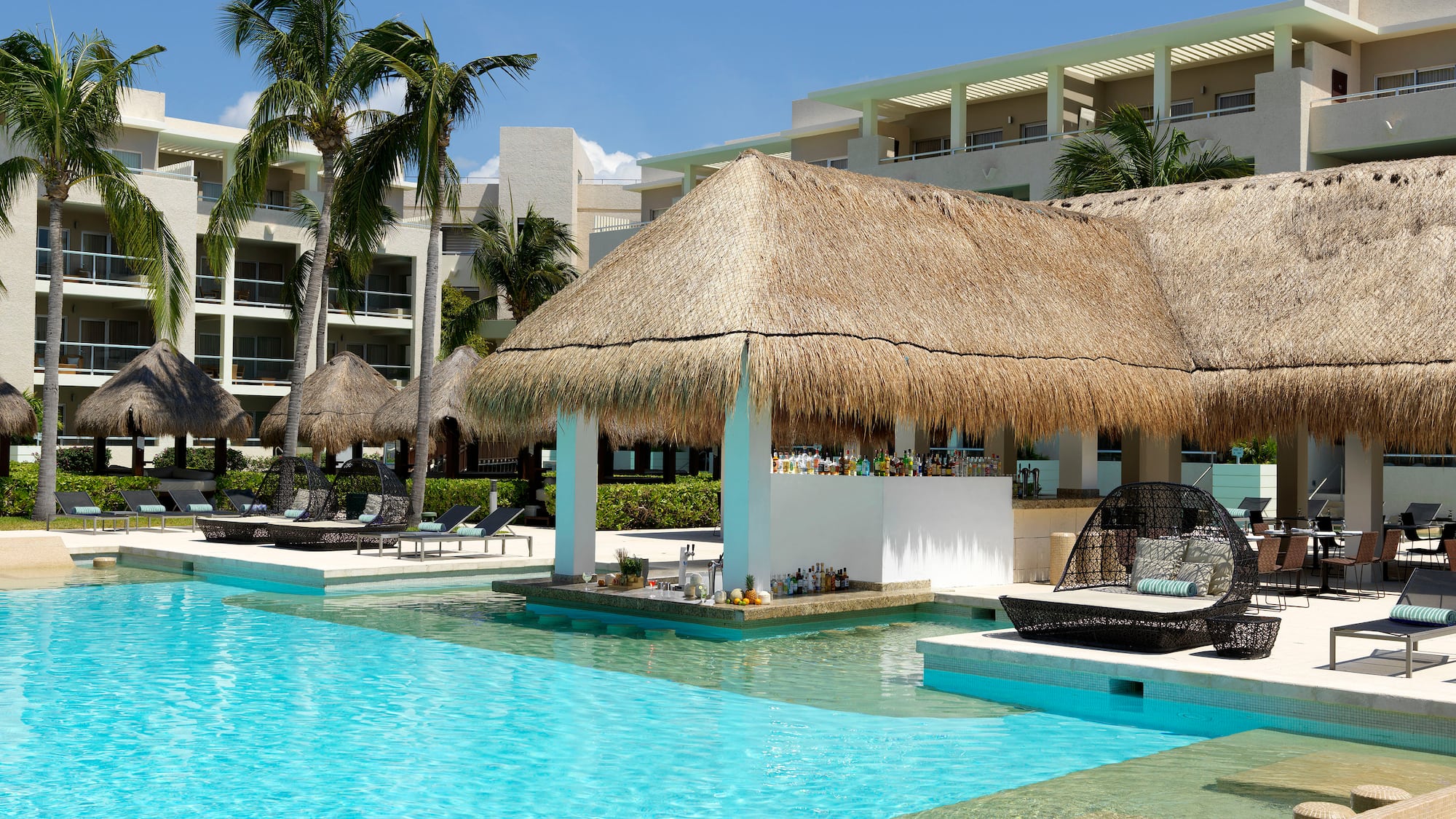 a pool with a thatched roof and lounge chairs