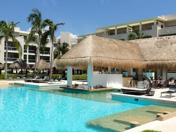 a pool with a thatched roof and lounge chairs