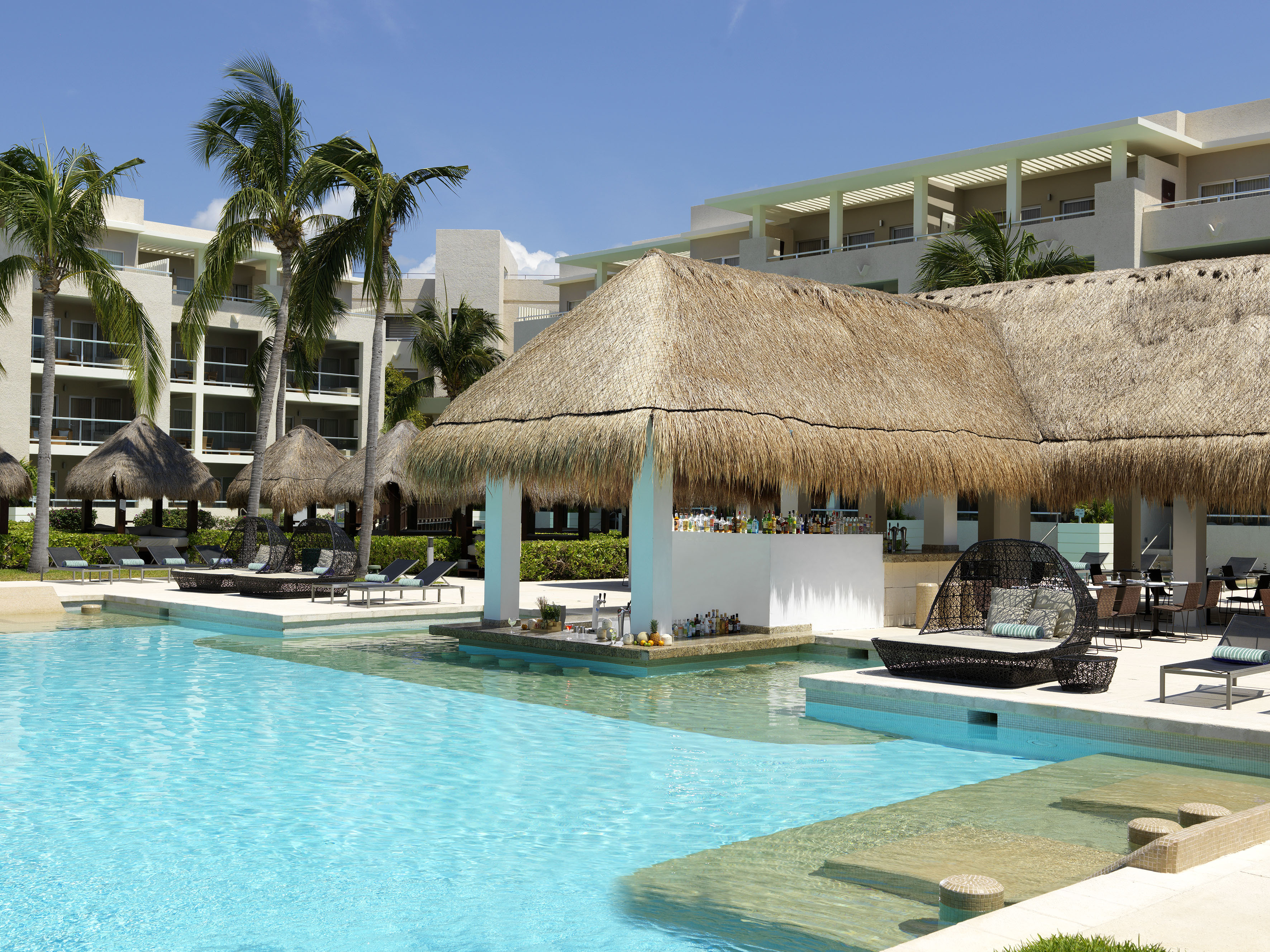 a pool with a thatched roof and lounge chairs