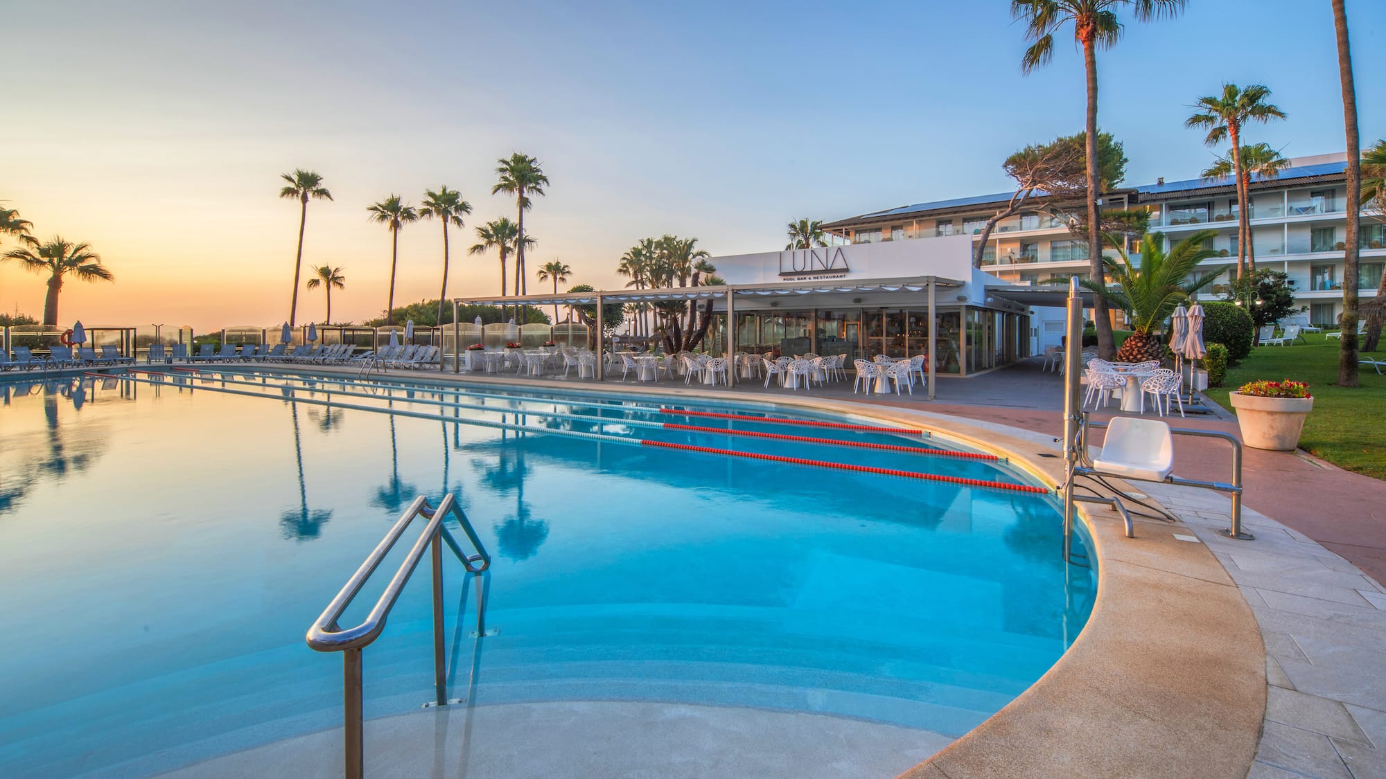 a pool with chairs and tables and palm trees