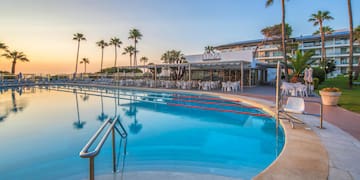 a pool with chairs and tables and palm trees