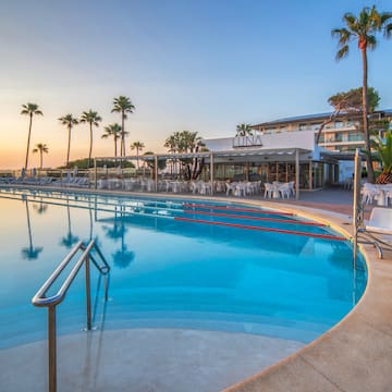 a pool with chairs and tables and palm trees