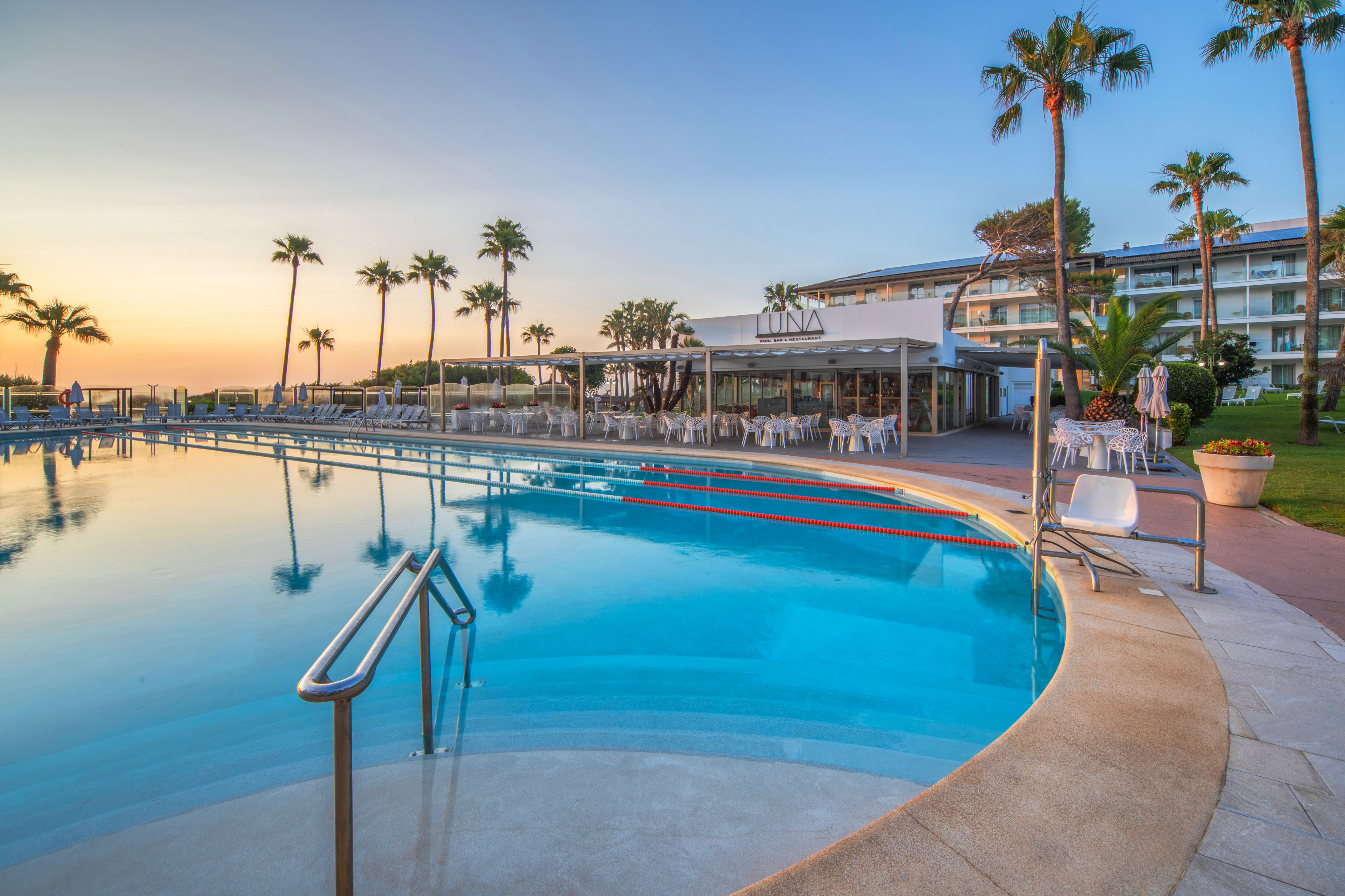 a pool with chairs and tables and palm trees