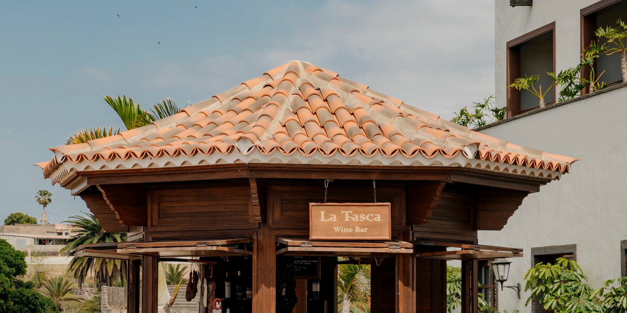 a wooden gazebo with chairs and a table in front of a building