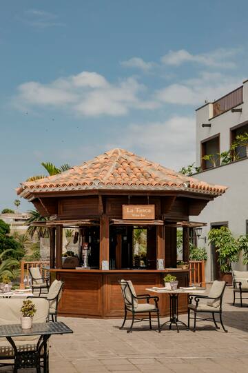 a wooden gazebo with chairs and a table in front of a building