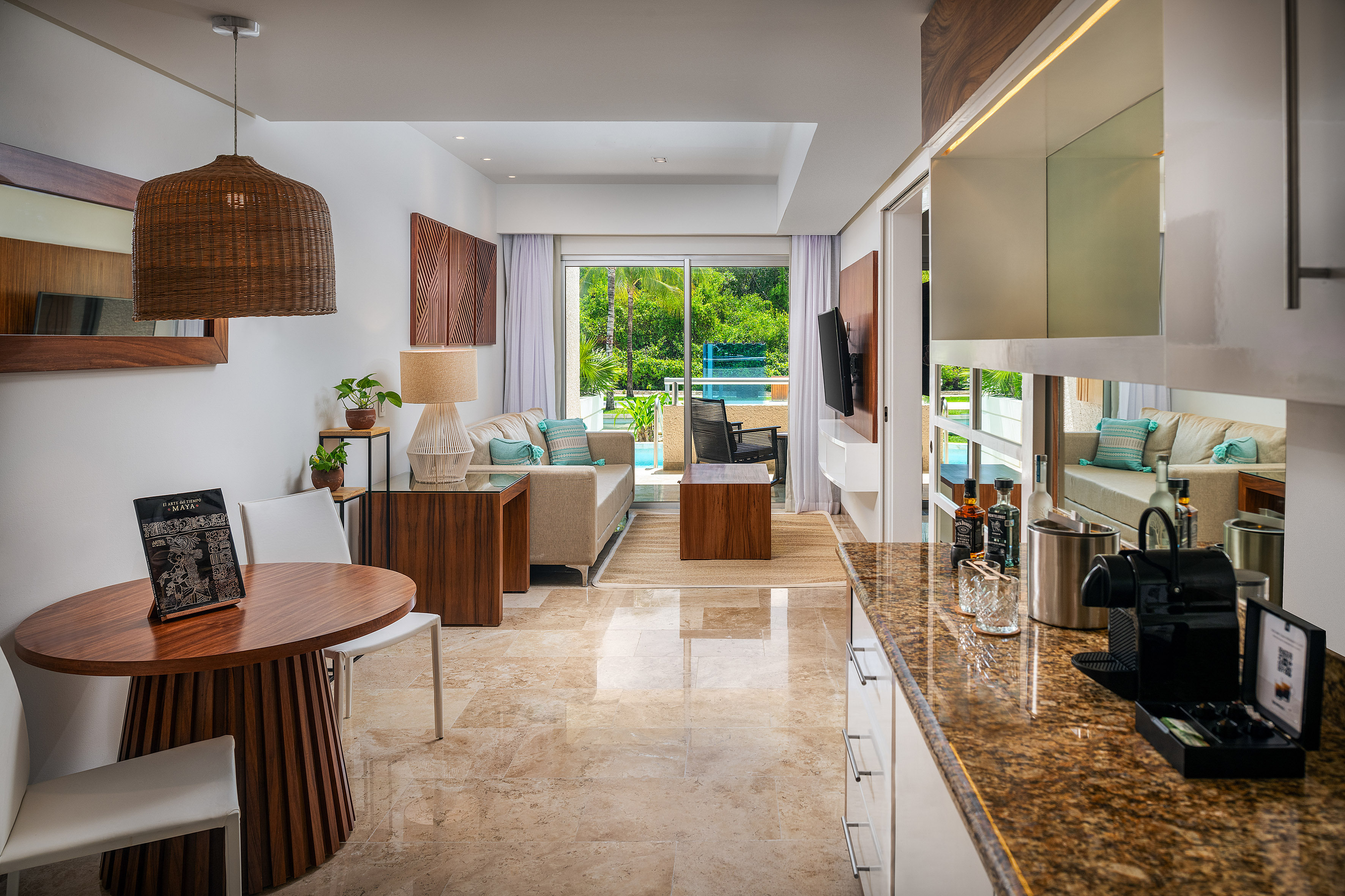 Modern hotel suite with living, dining, kitchenette, and pool-view balcony.