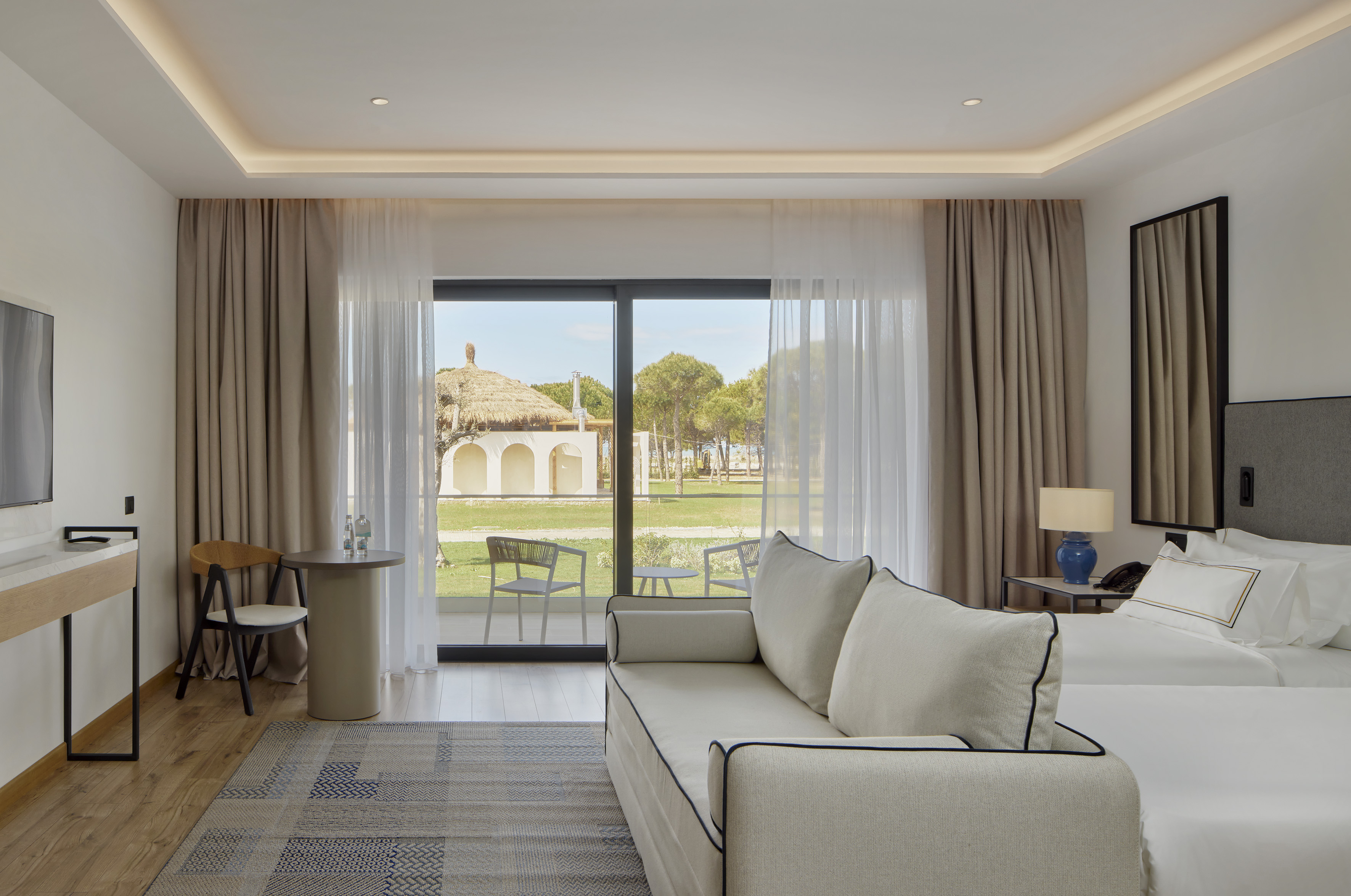 Stylish hotel room with sofa, twin beds, and an outdoor resort view.