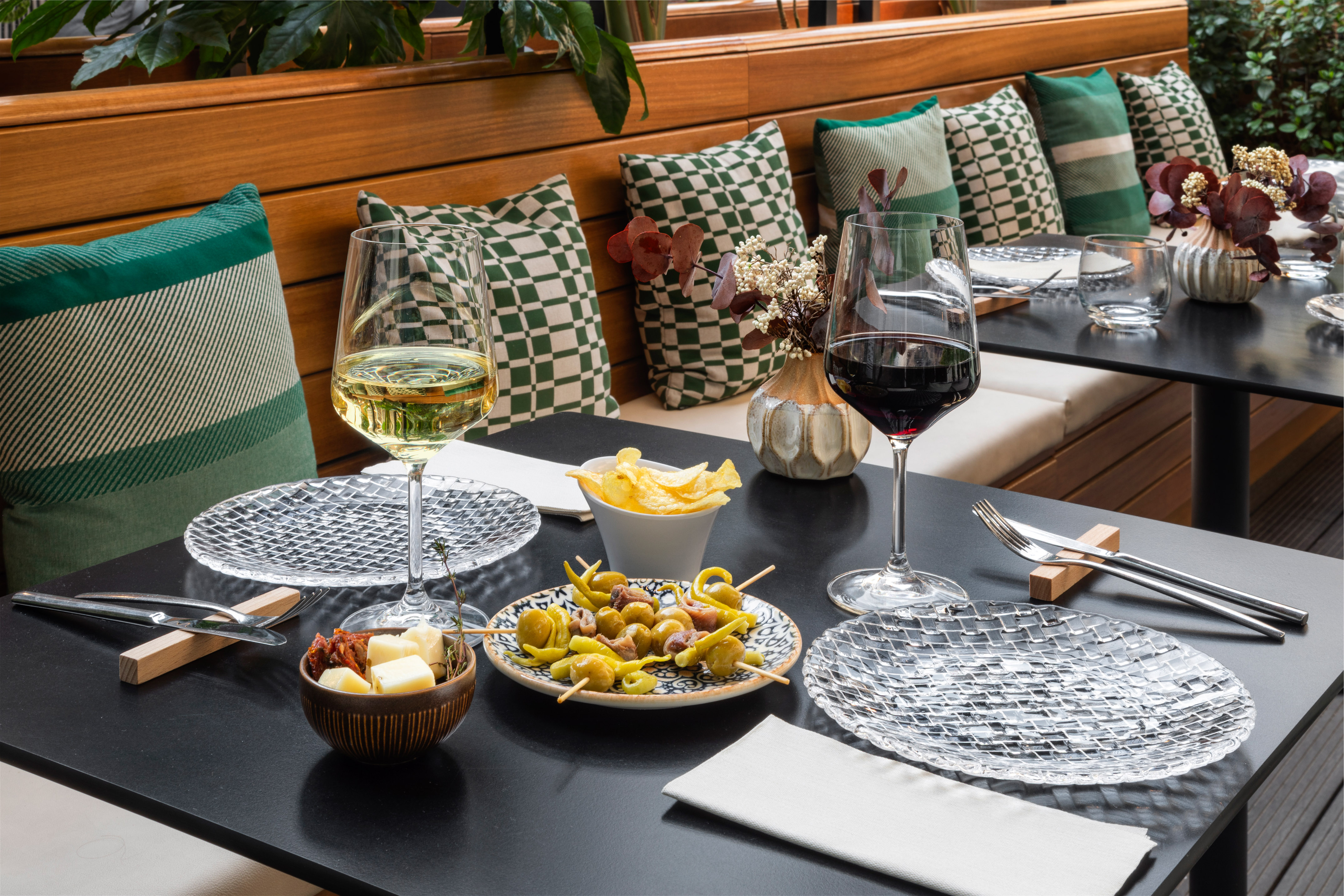 Restaurant table with red & white wine, tapas, and stylish green cushions.