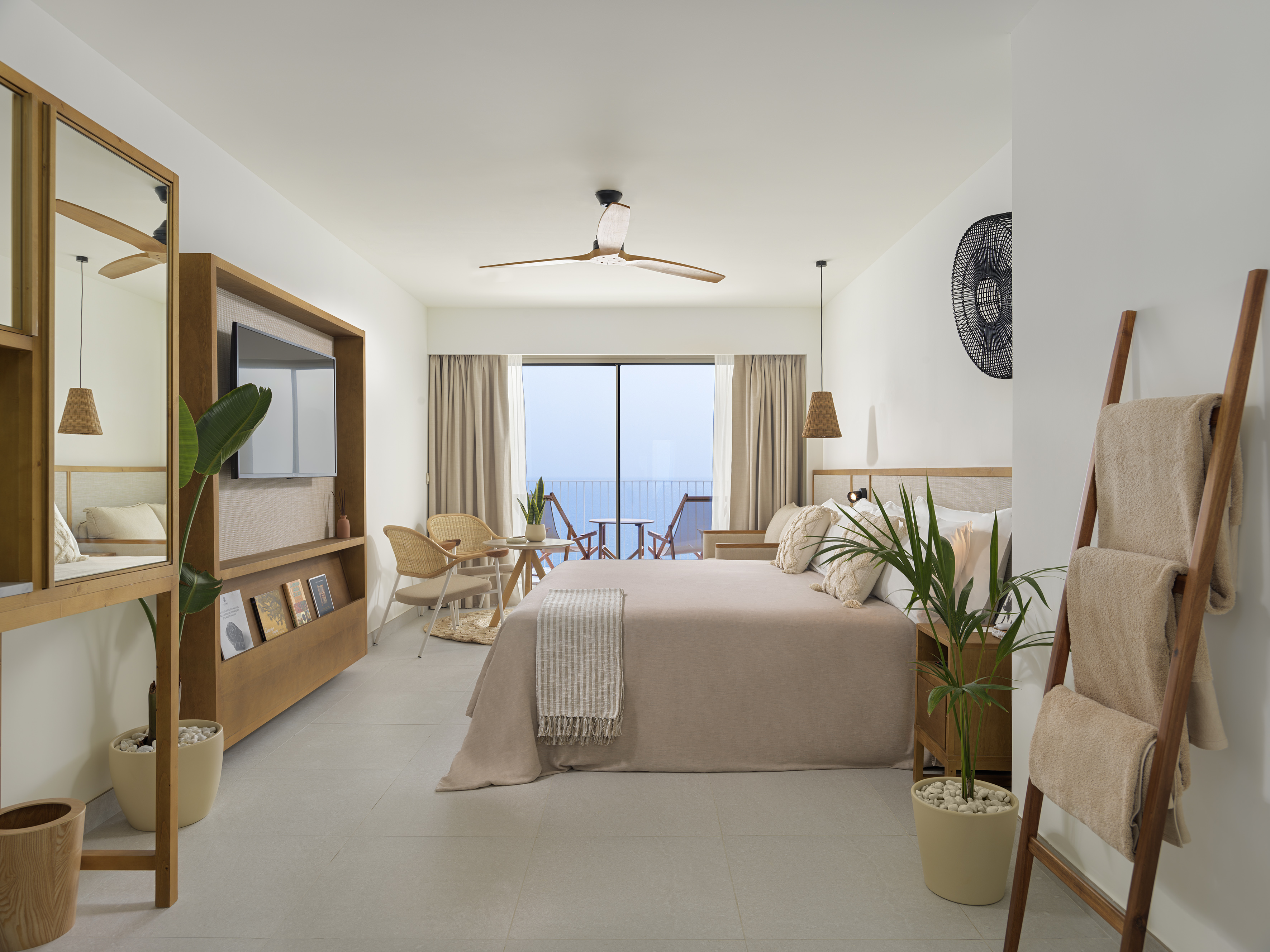 Coastal hotel room with ocean view balcony, king bed, and natural accents.