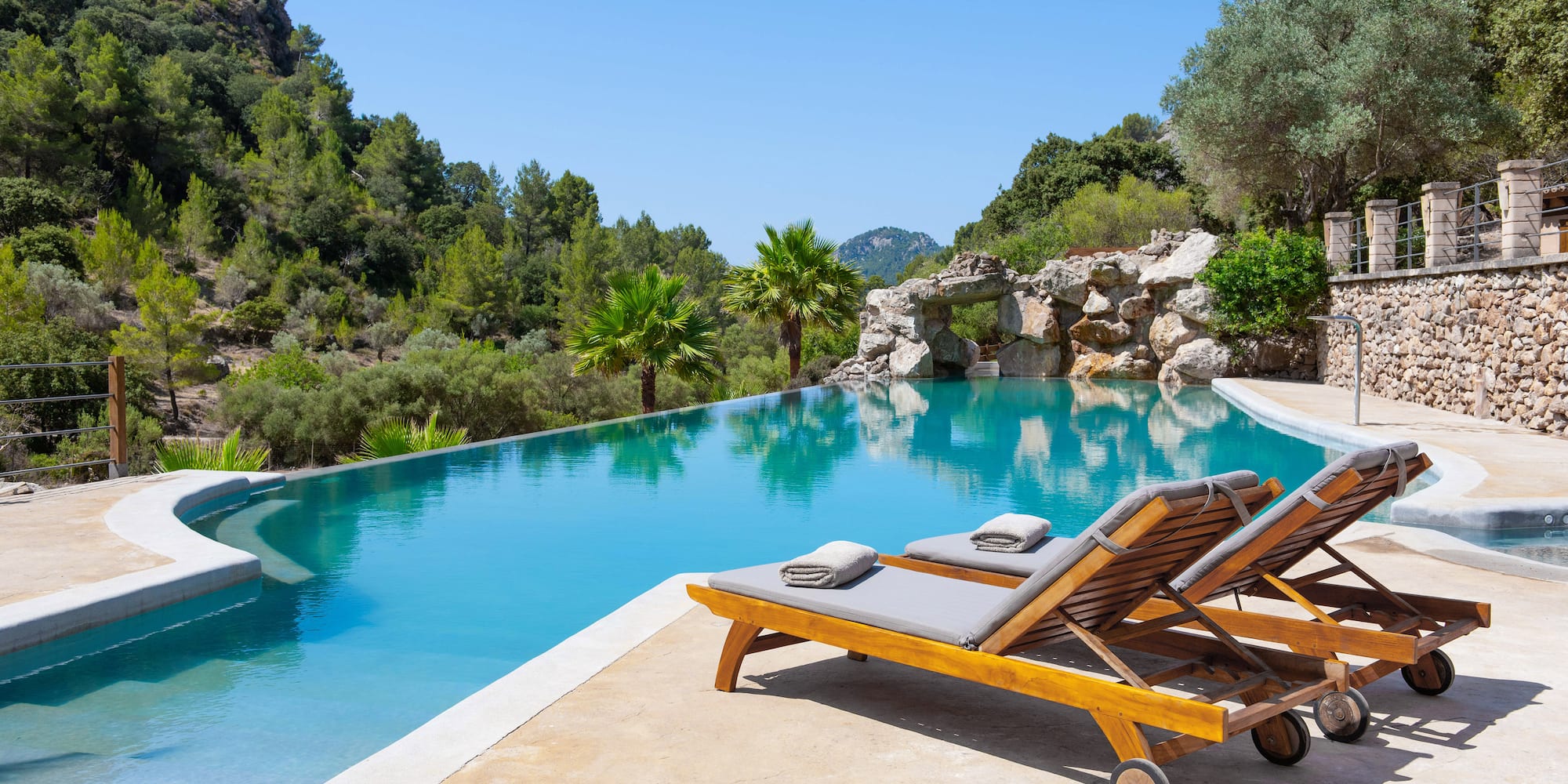 a pool with lounge chairs and trees in the background
