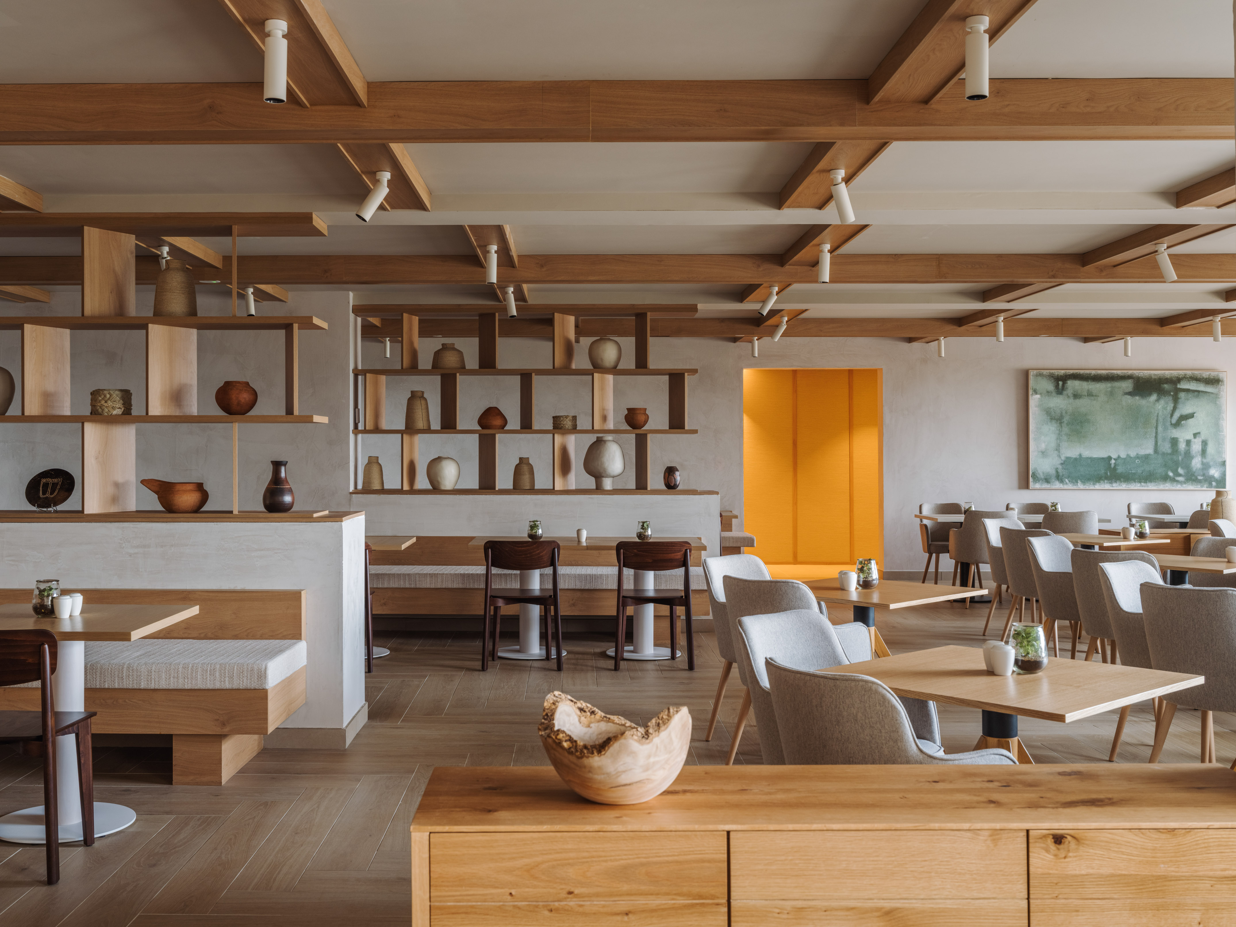 Modern restaurant interior: wood beams, dining tables, banquettes, decorative shelves.