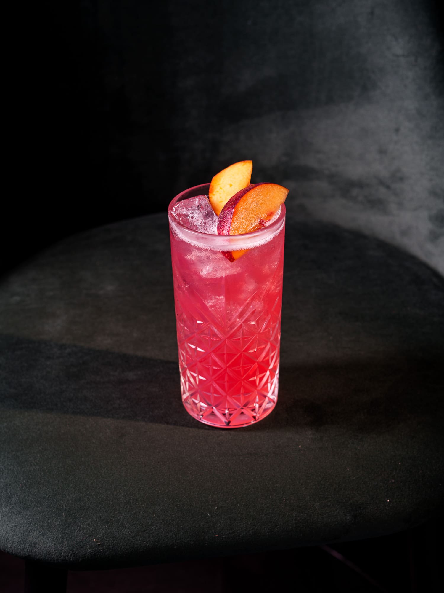 a glass of pink drink with fruit slices on top