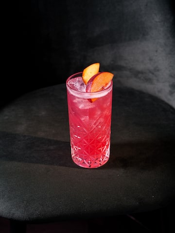 a glass of pink drink with fruit slices on top