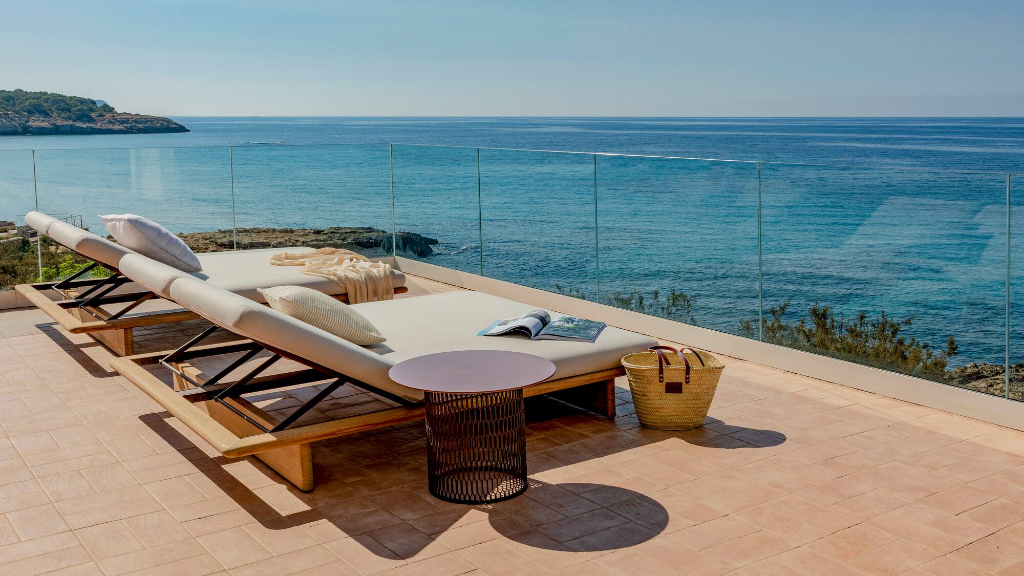a deck with a chair and a table overlooking the ocean