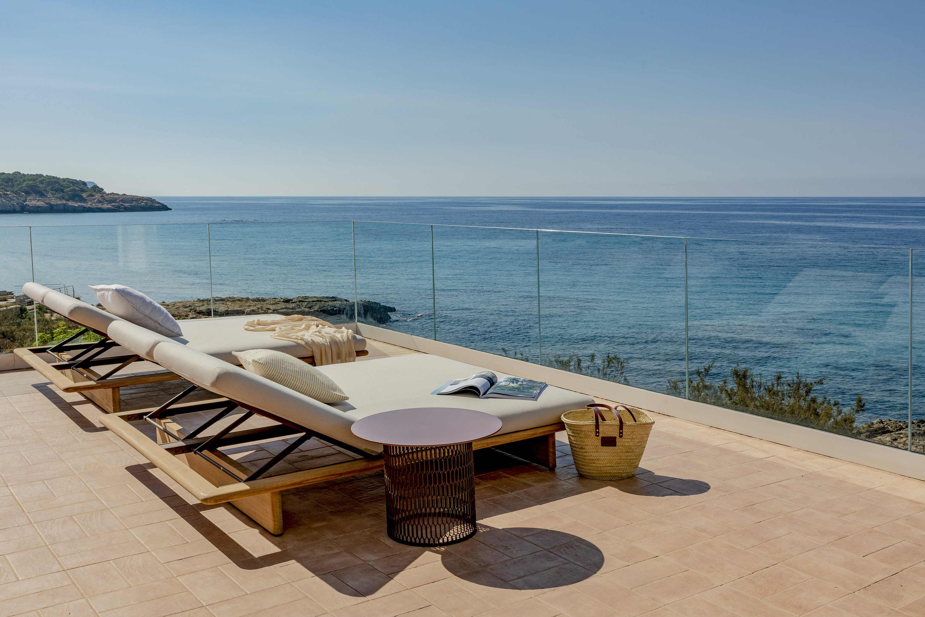 a deck with a chair and a table overlooking the ocean