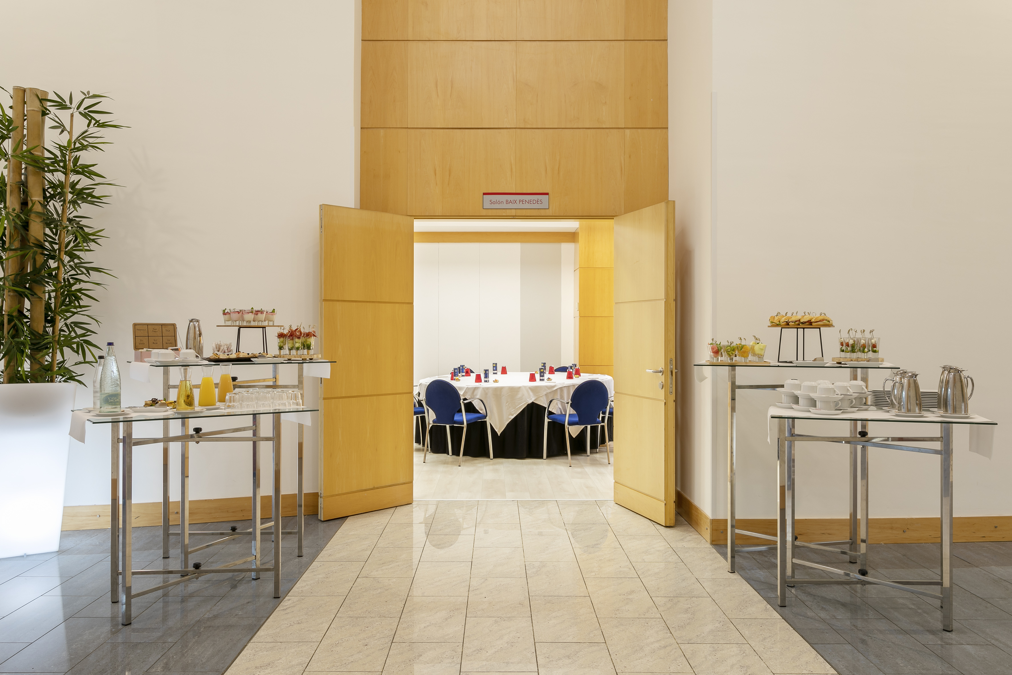 Hotel conference hallway with catering buffet, open doors to a meeting room.
