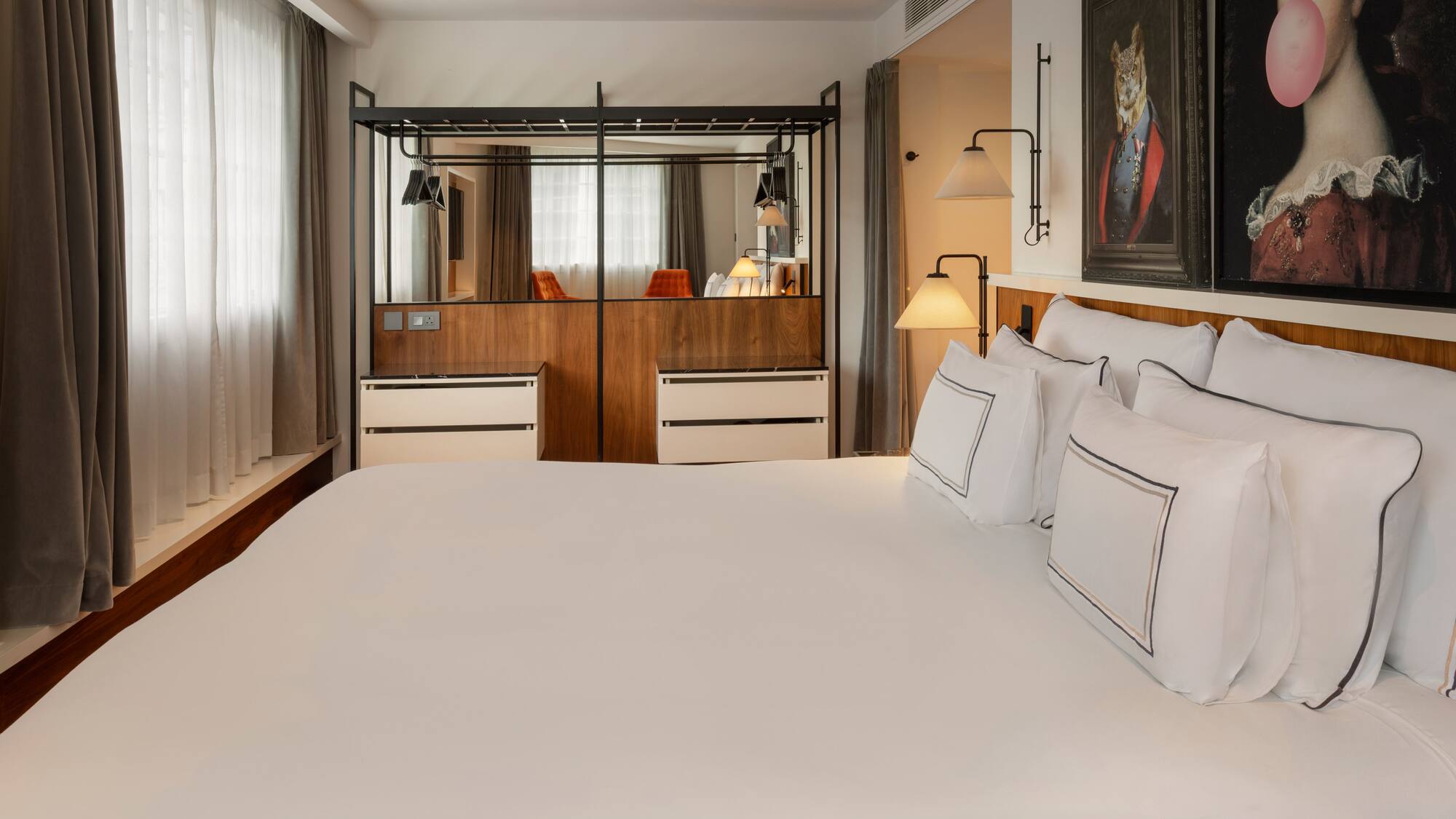 Bright hotel bedroom with white bed, creative wall art, and mirrored closet.