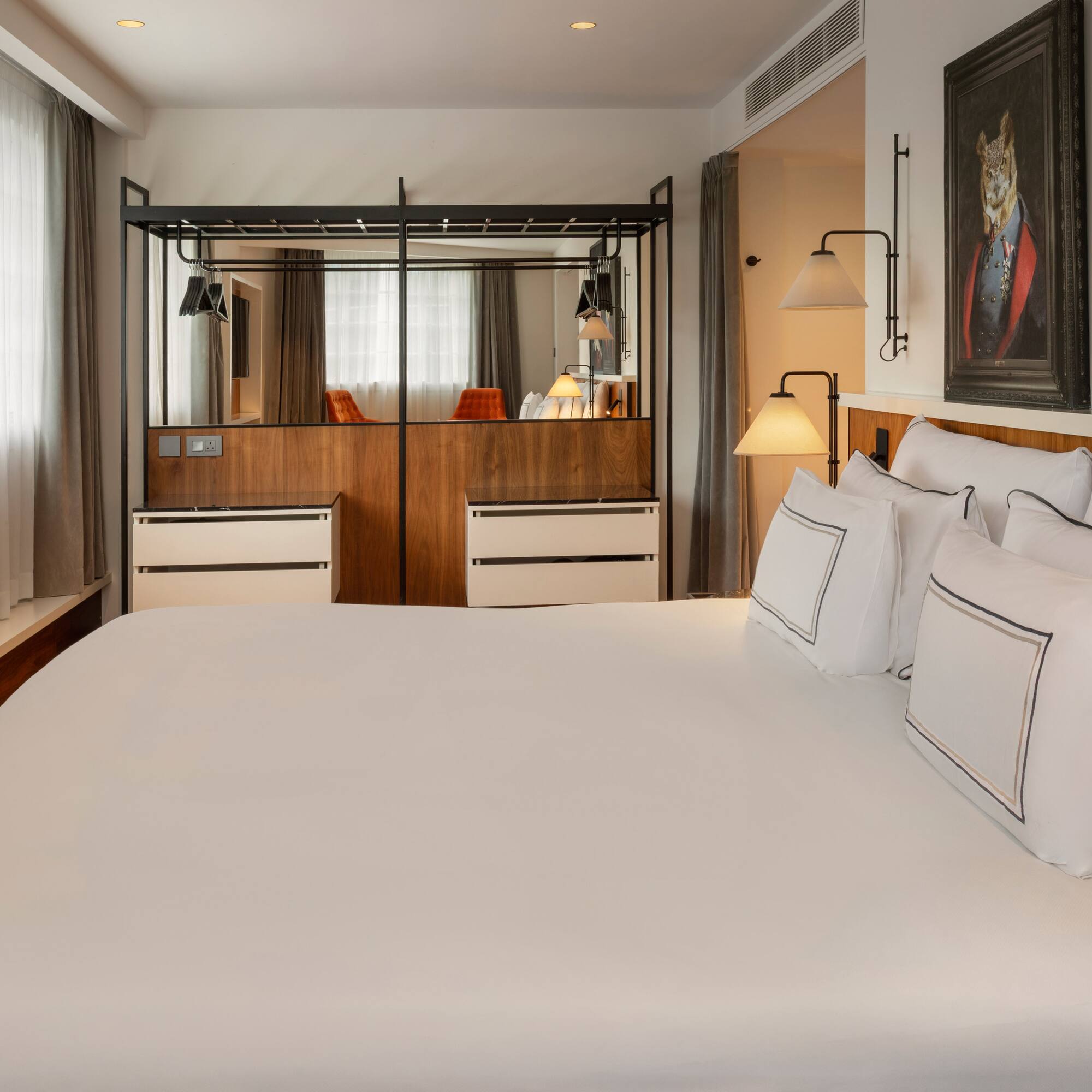 Bright hotel bedroom with white bed, creative wall art, and mirrored closet.
