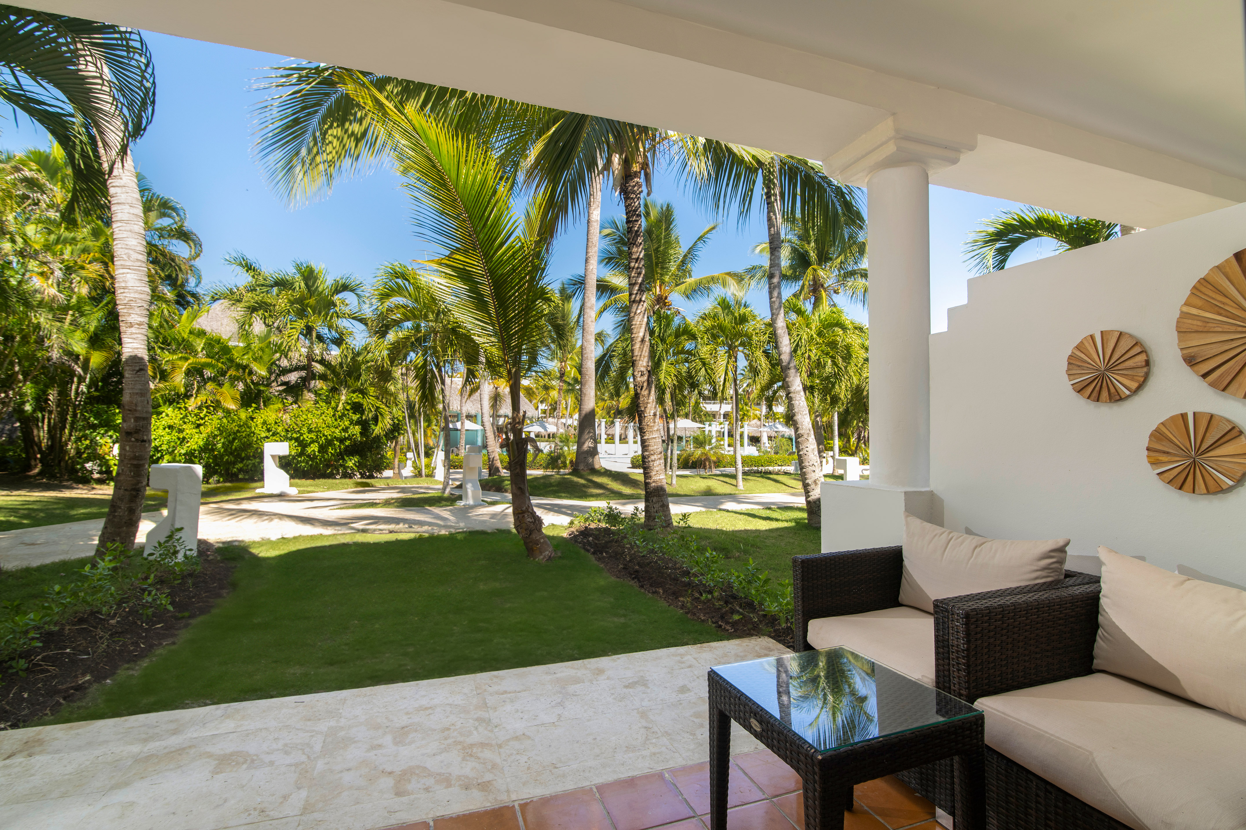 Tropical resort patio with outdoor furniture overlooking lush palm garden.