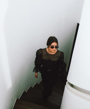 a woman in a black dress and sunglasses walking up stairs