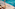 Resort poolside: two lounge chairs, white umbrella, and shimmering blue water.