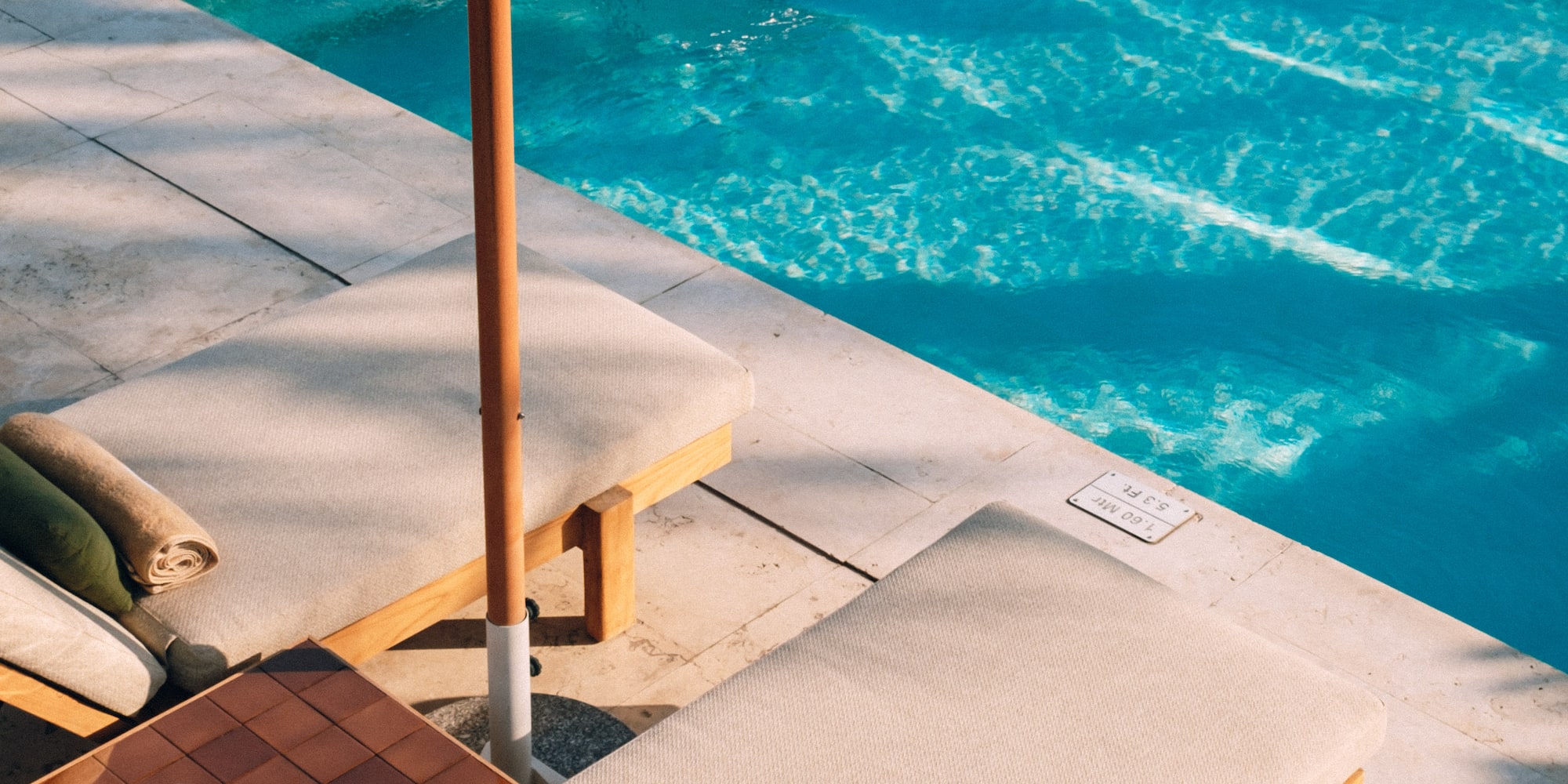 a pool with a lounge chair and umbrella