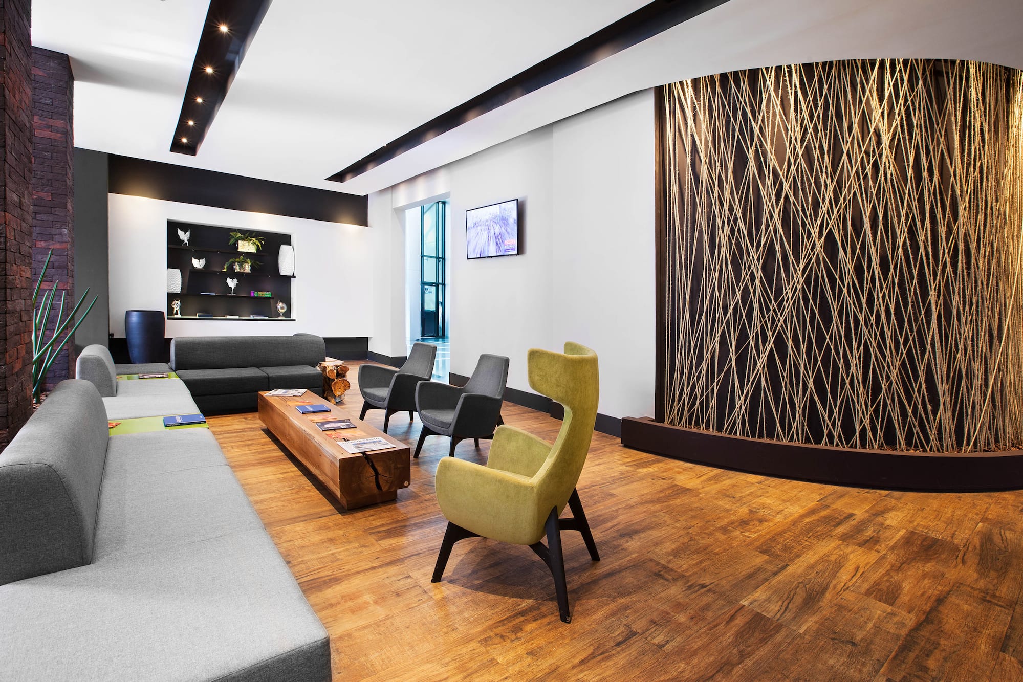 Modern waiting room with wood floors, seating, and abstract string wall.