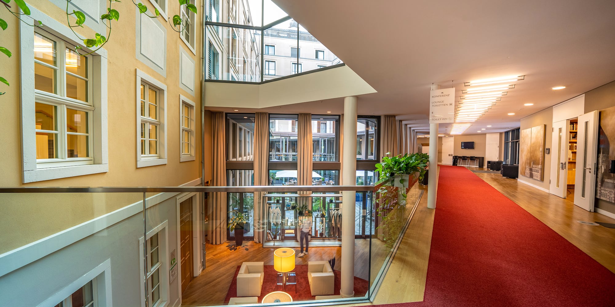a hallway with a red carpet and a glass wall