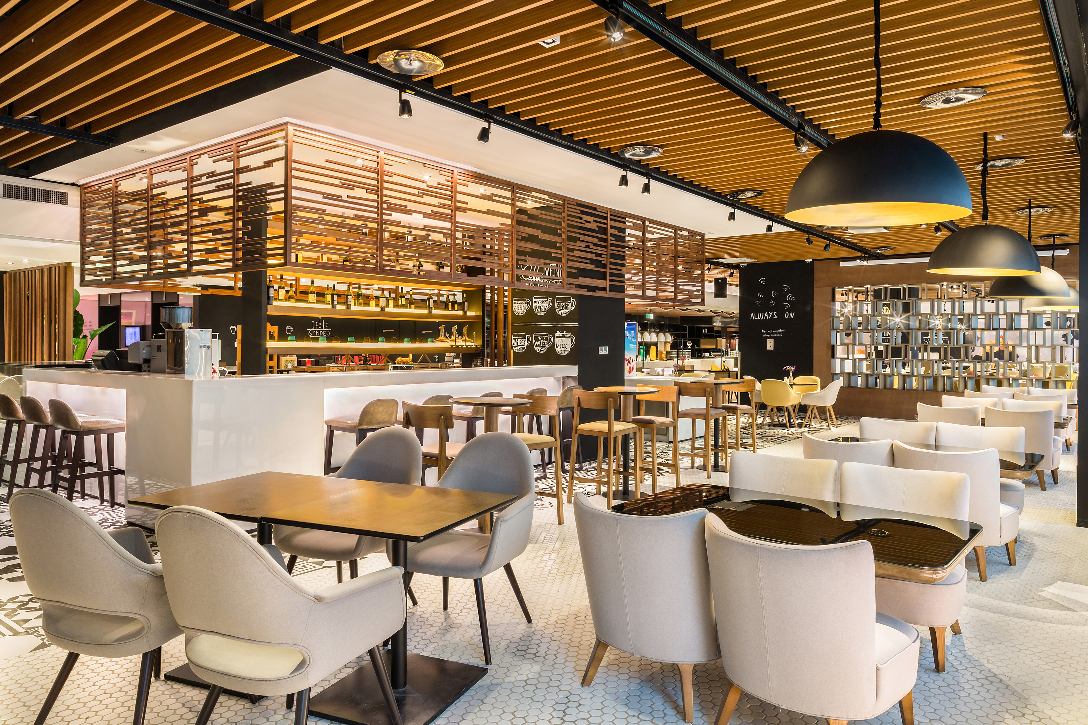 Modern cafe interior with a sleek bar, varied seating, and warm wood ceiling design.