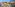 Coastal resort with orange hotels, sports courts, swimming pools, ocean, and mountains.