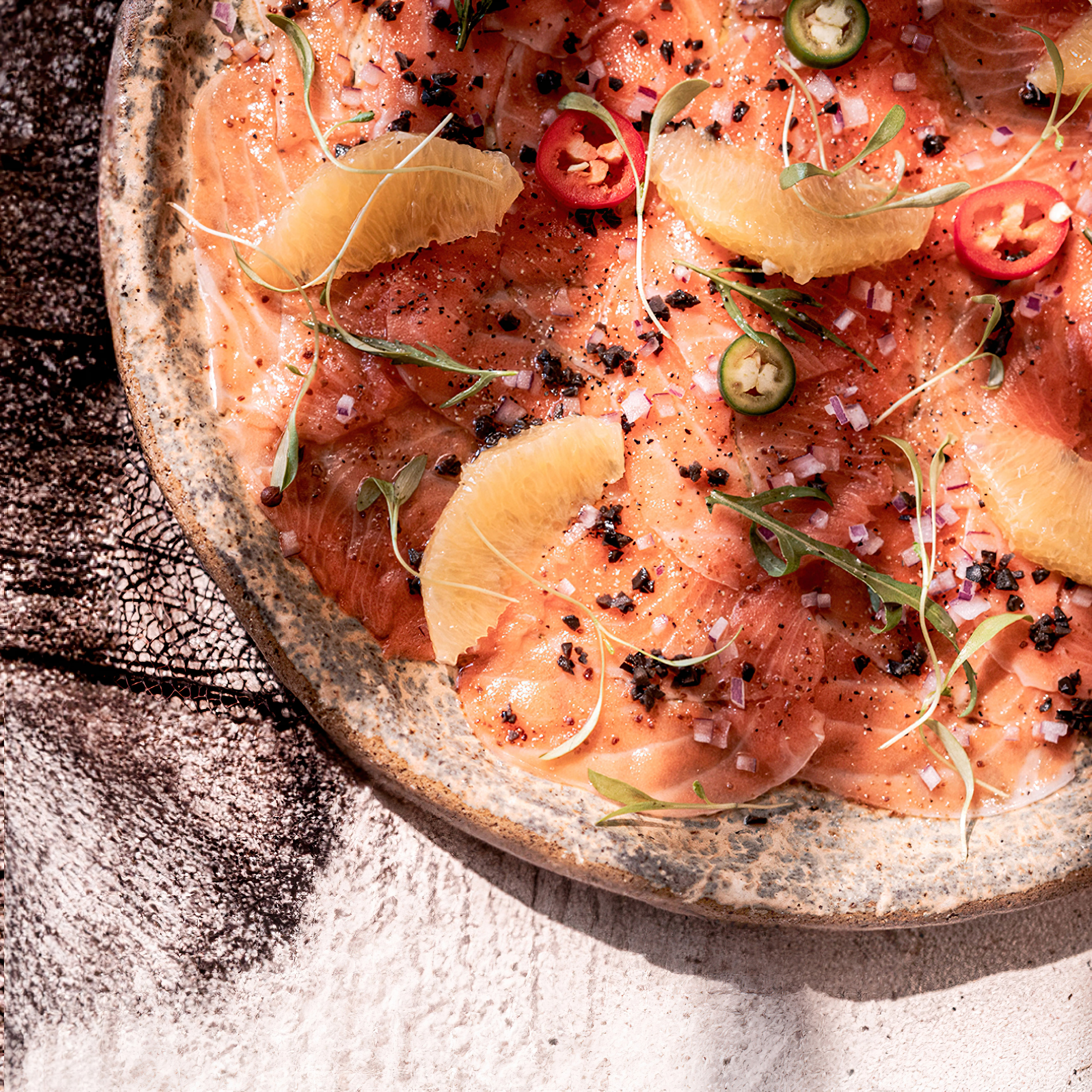 Fresh salmon carpaccio with grapefruit, chili, red onion, and microgreens.