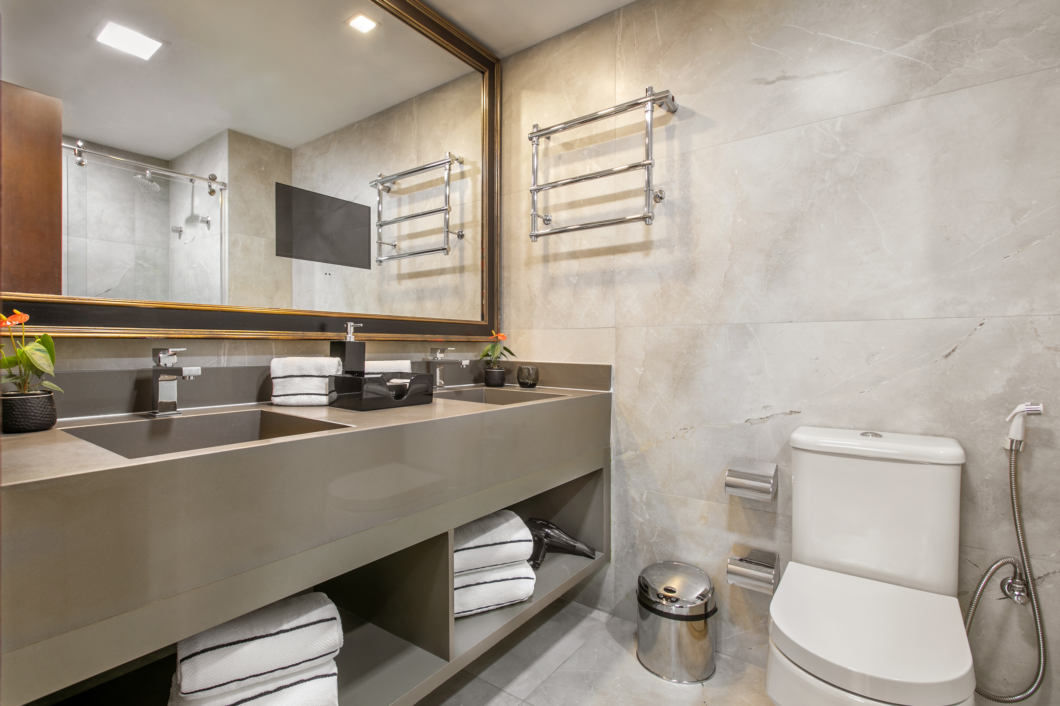 Modern bathroom with double vanity, grey marble tiles, large mirror, and toilet.