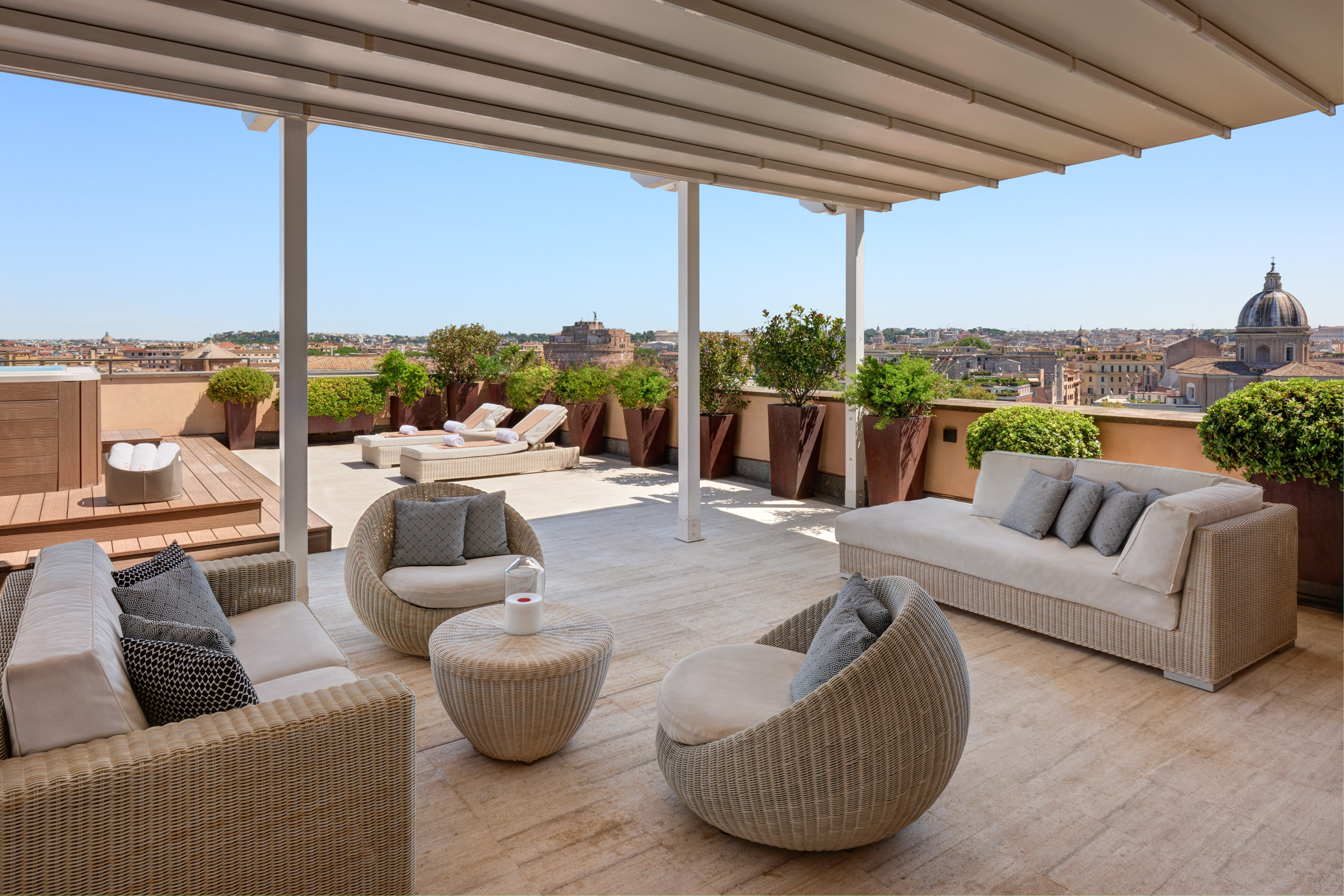 Rome rooftop terrace with wicker seating, sun loungers, and city views.