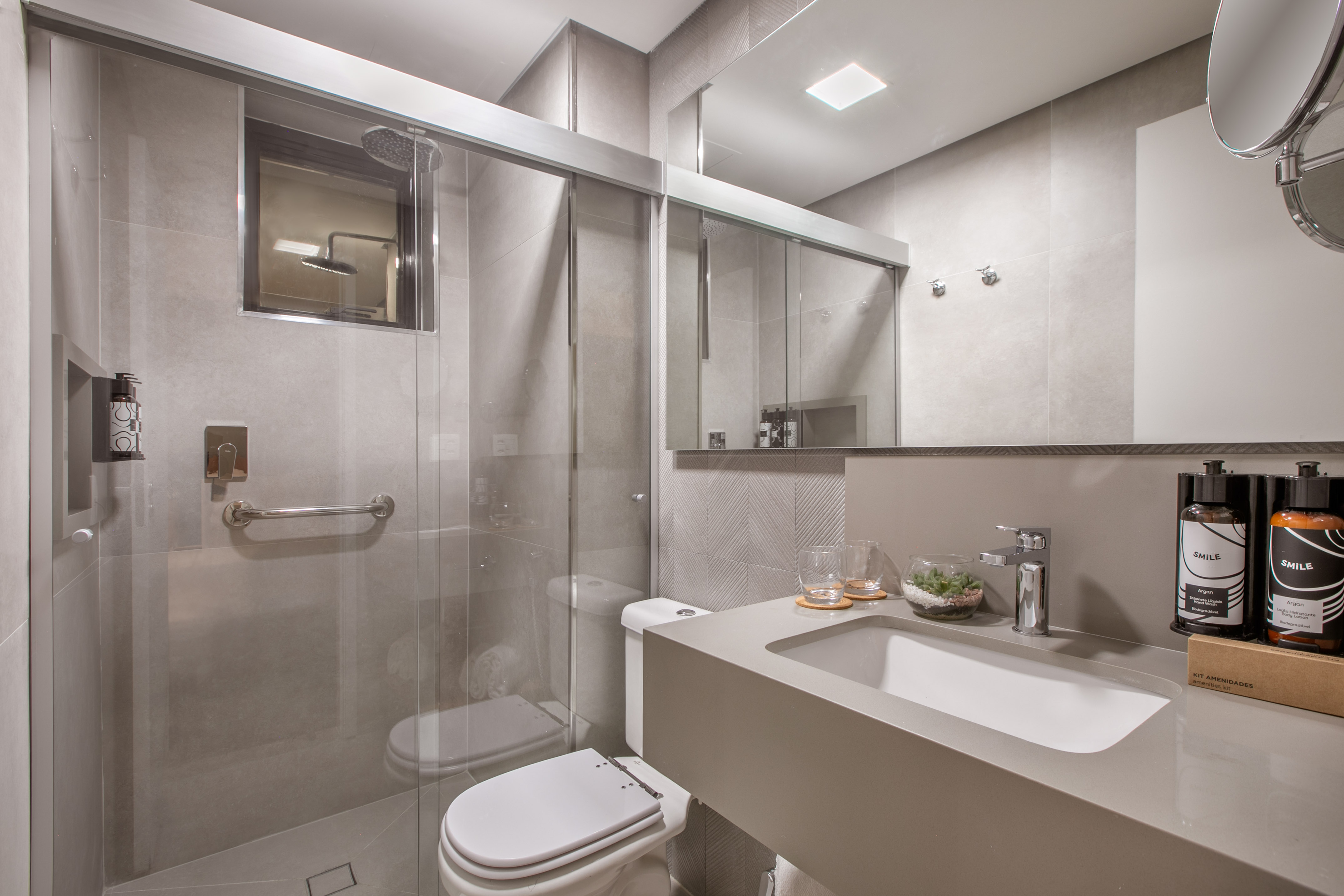 Modern grey bathroom with glass shower, toilet, and contemporary vanity.