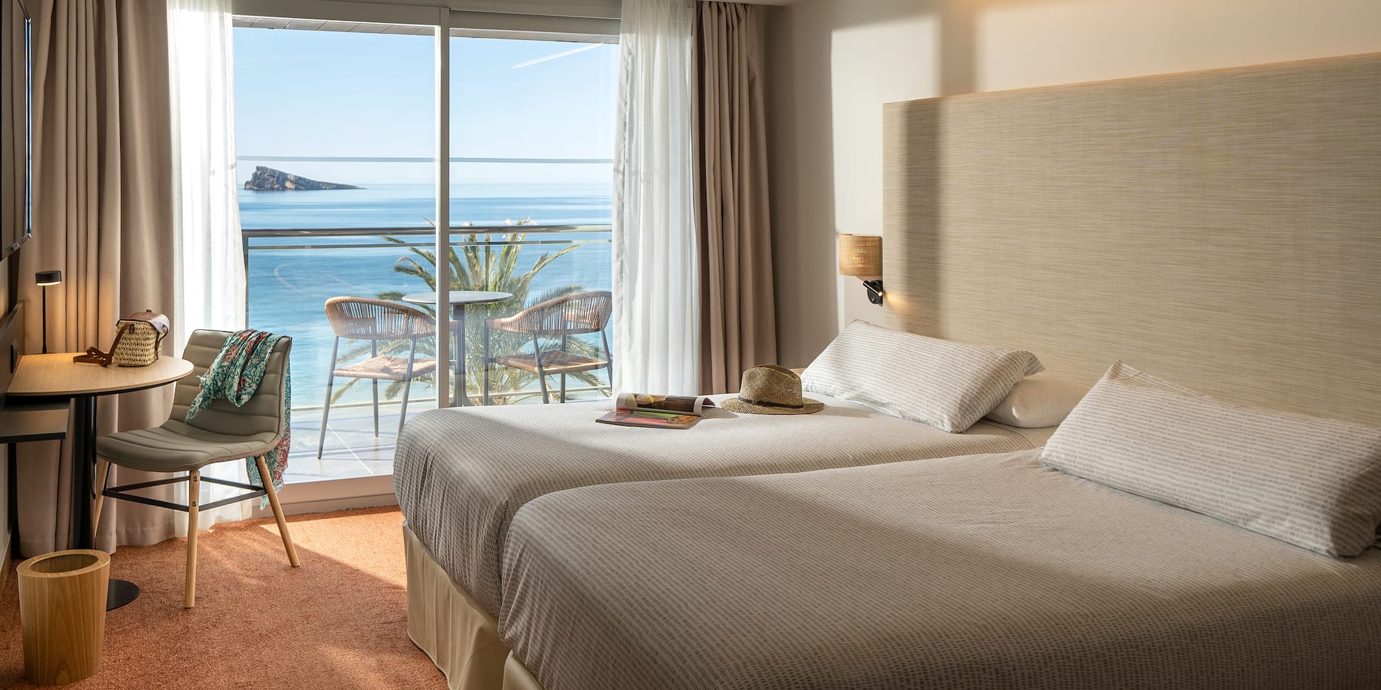 two beds in a room with a view of the ocean