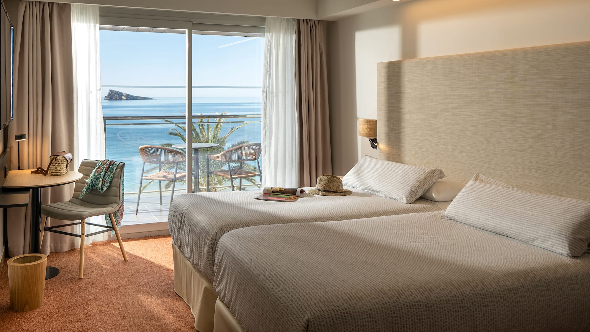 two beds in a room with a view of the ocean