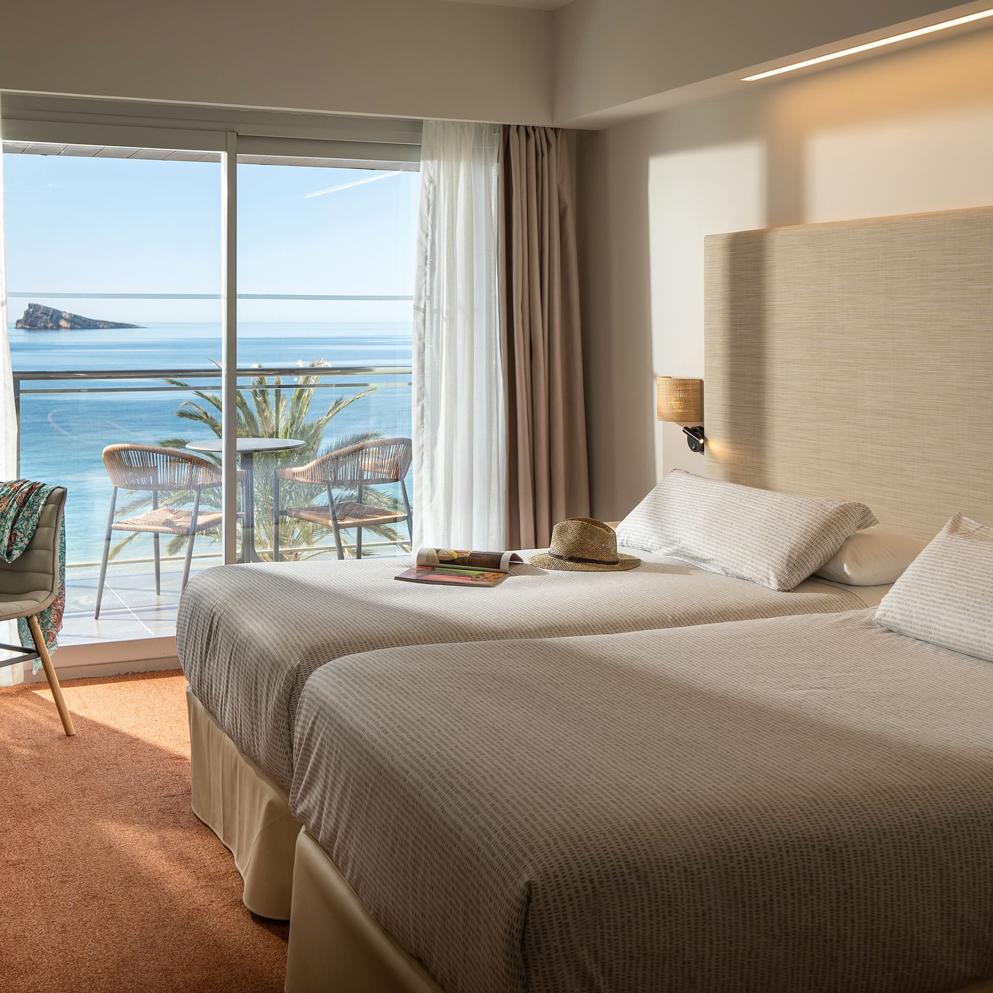 two beds in a room with a view of the ocean