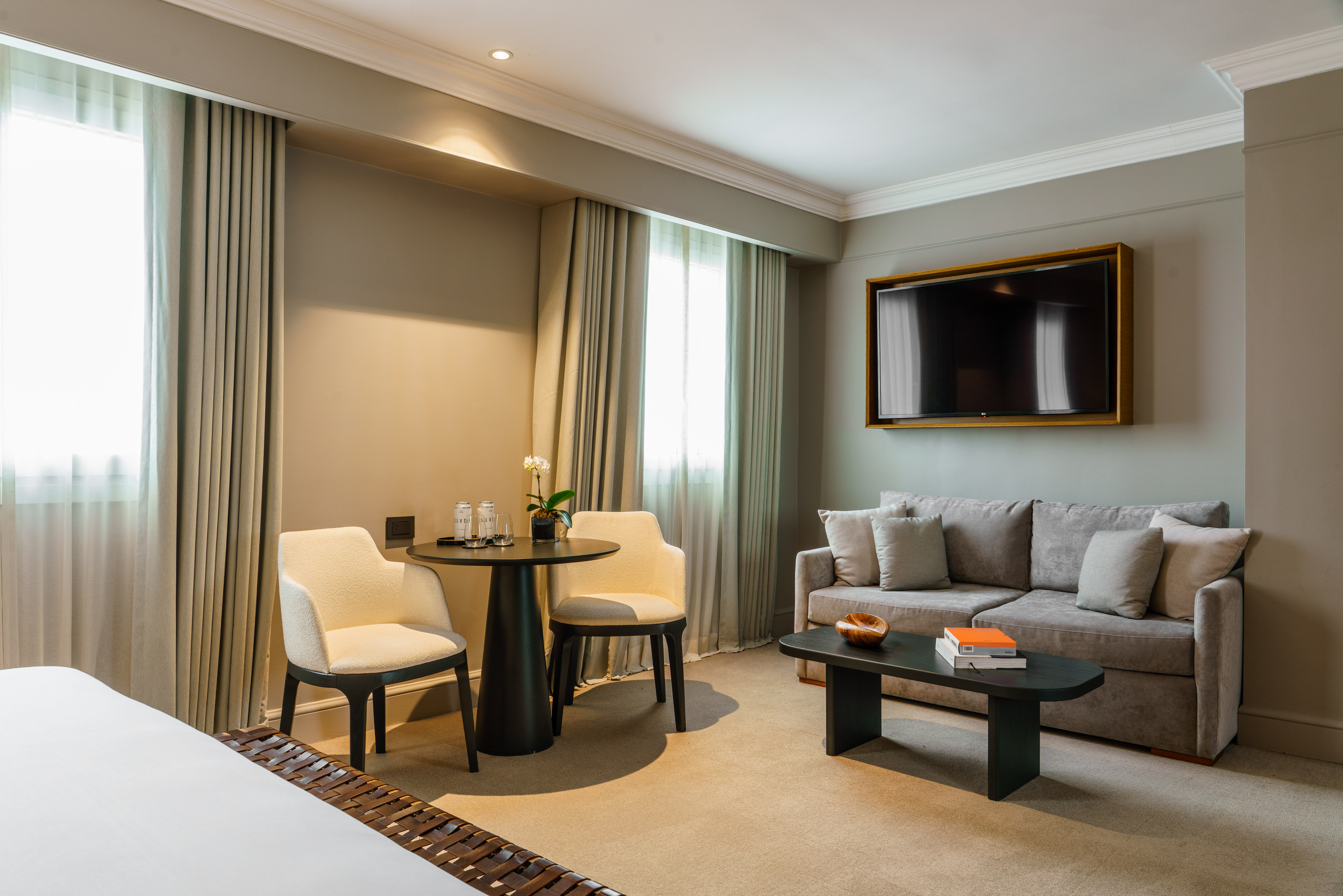 Comfortable hotel suite living room with sofa, wall TV, and dining nook.