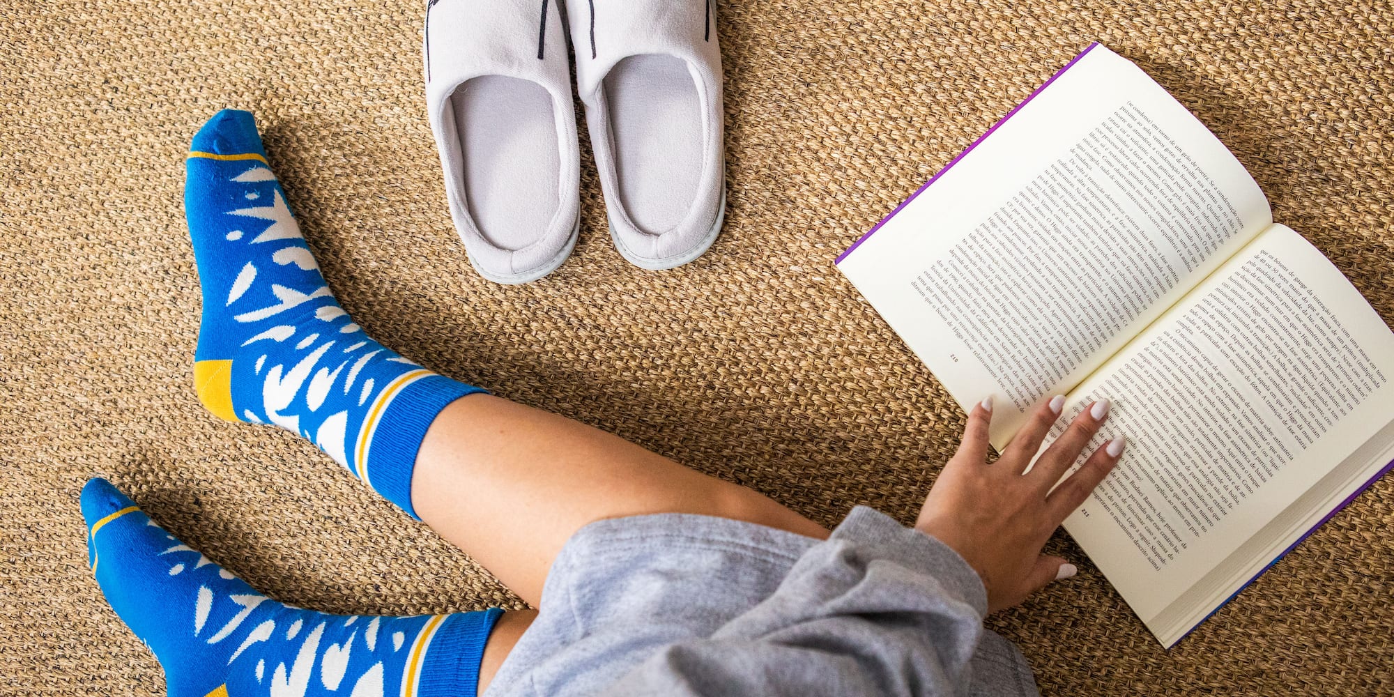 a person reading a book next to slippers