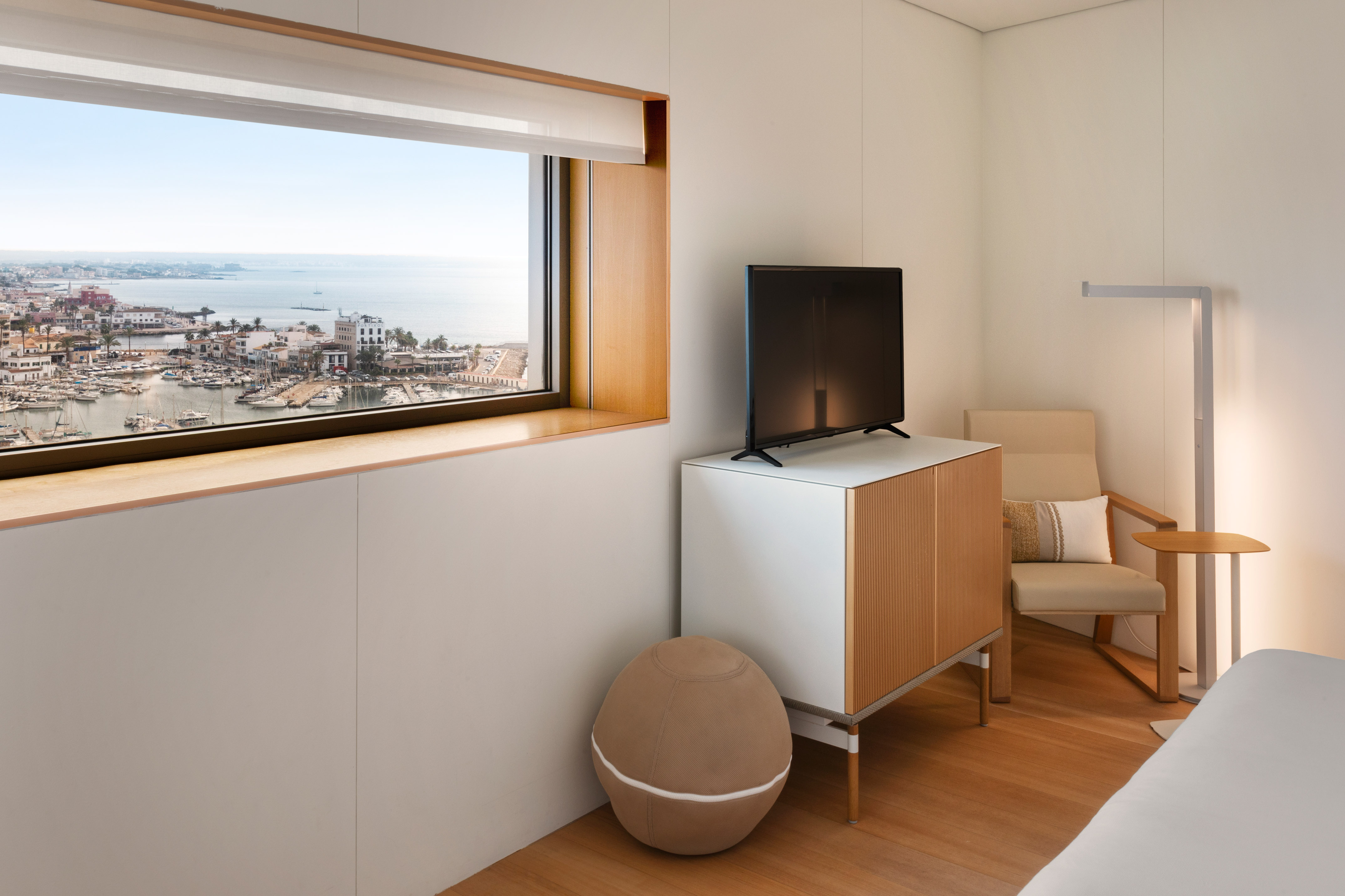 Modern coastal room with harbor view, boats, TV, and minimalist decor.