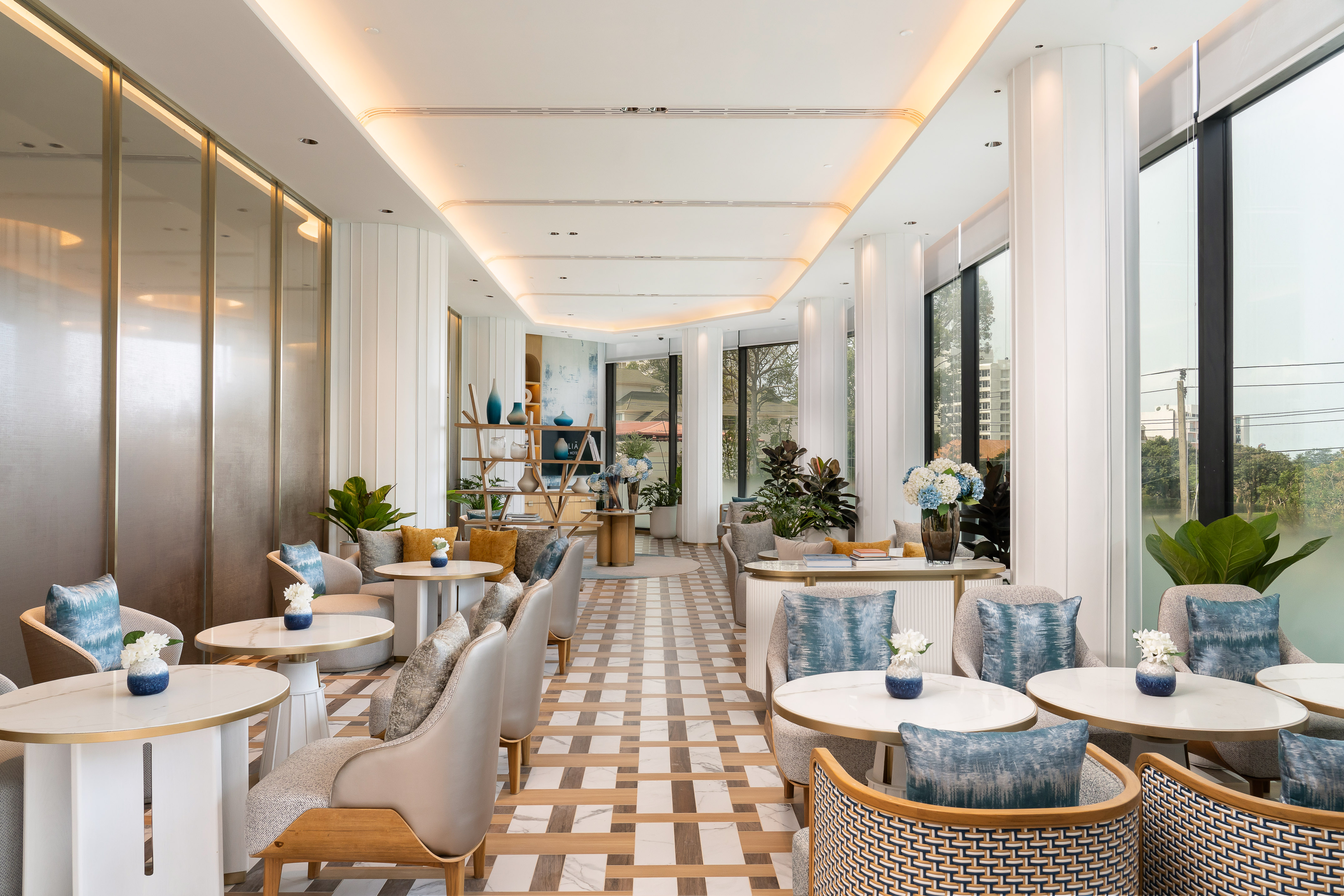 Modern luxury lounge with elegant seating, blue and gold decor, and natural light.