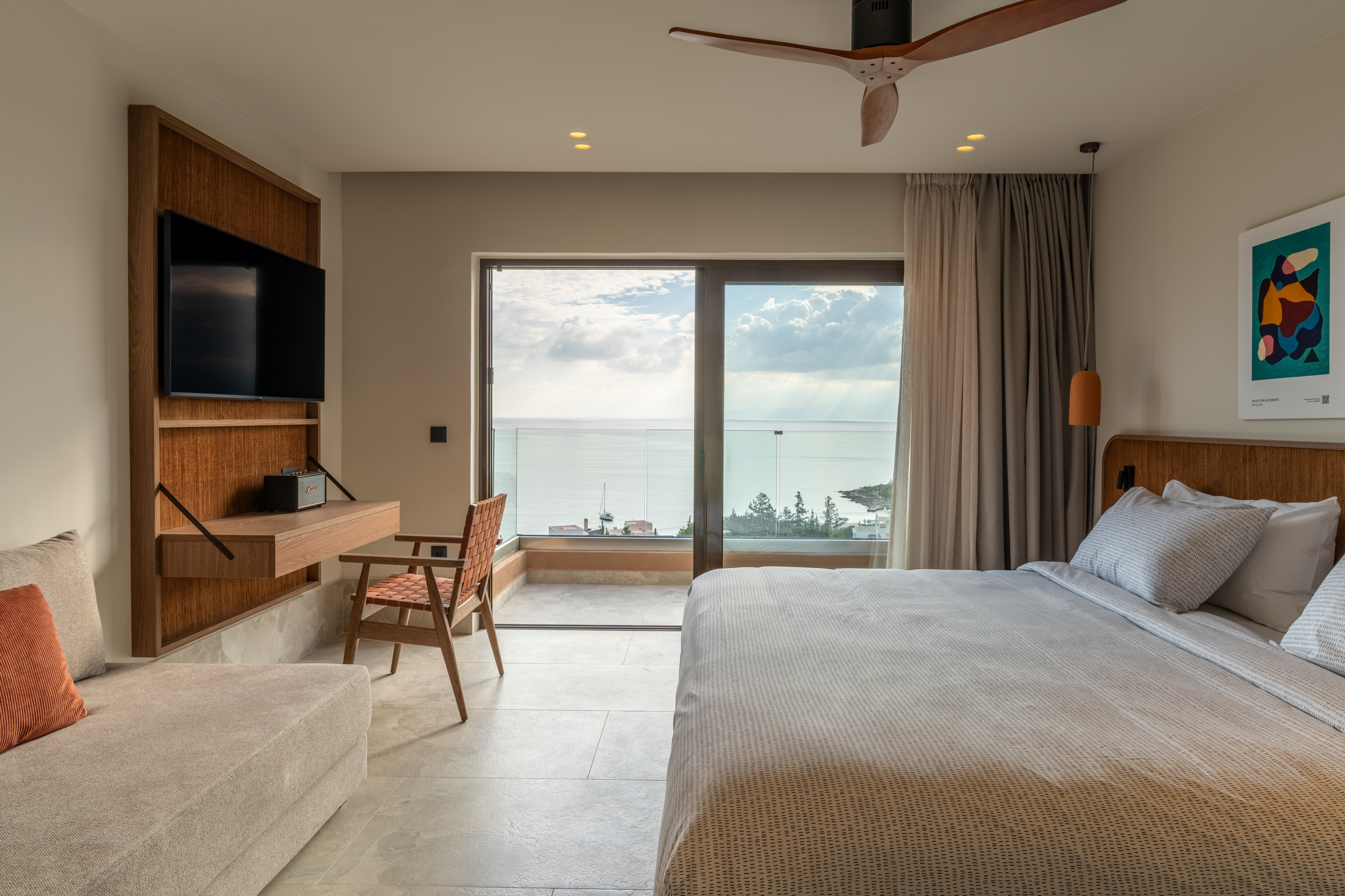 Modern hotel bedroom with sea view balcony, large bed, and contemporary furnishings.
