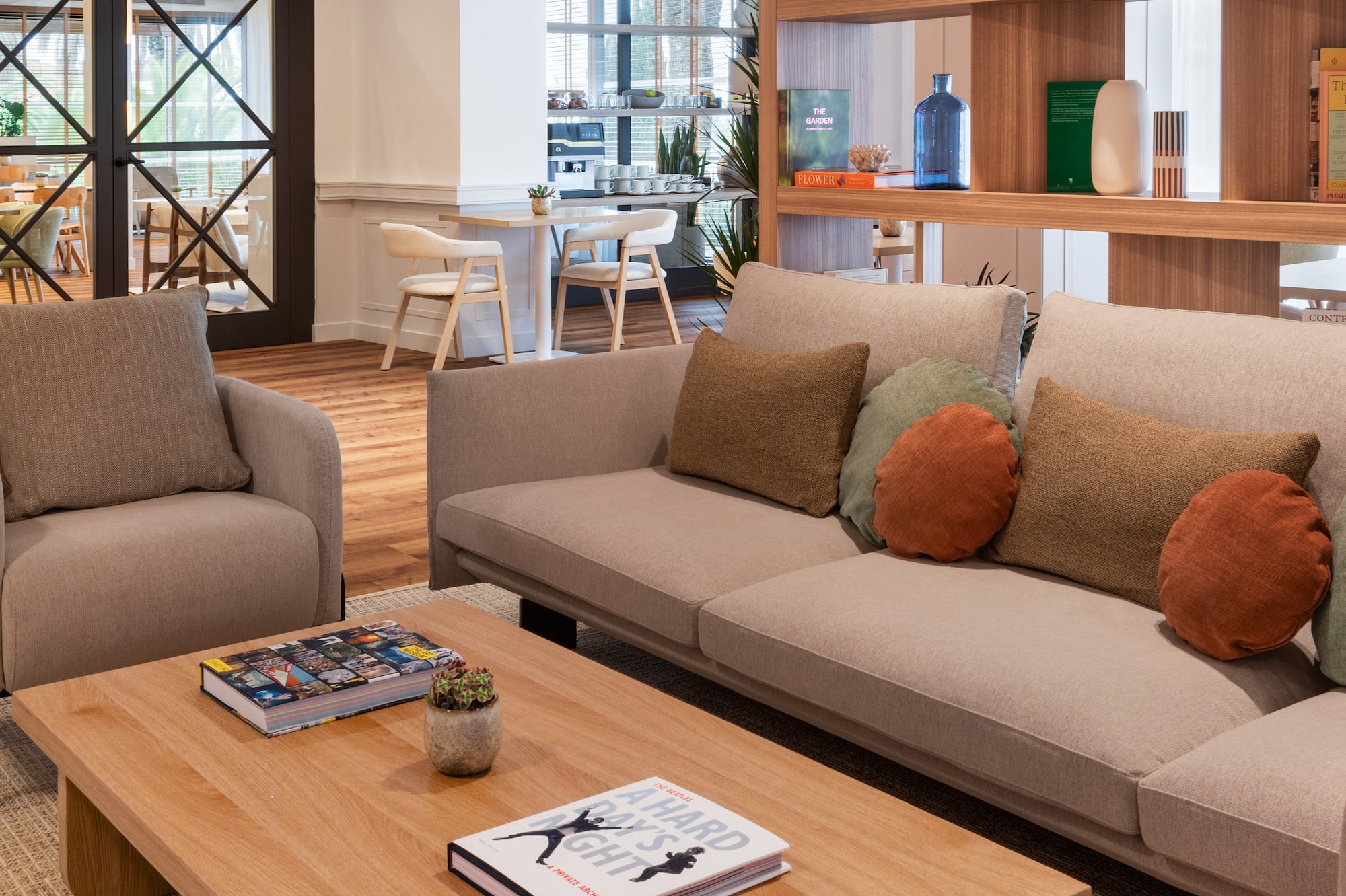 Modern hotel lounge with comfortable sofa, wooden coffee table, and stylish bookshelf.