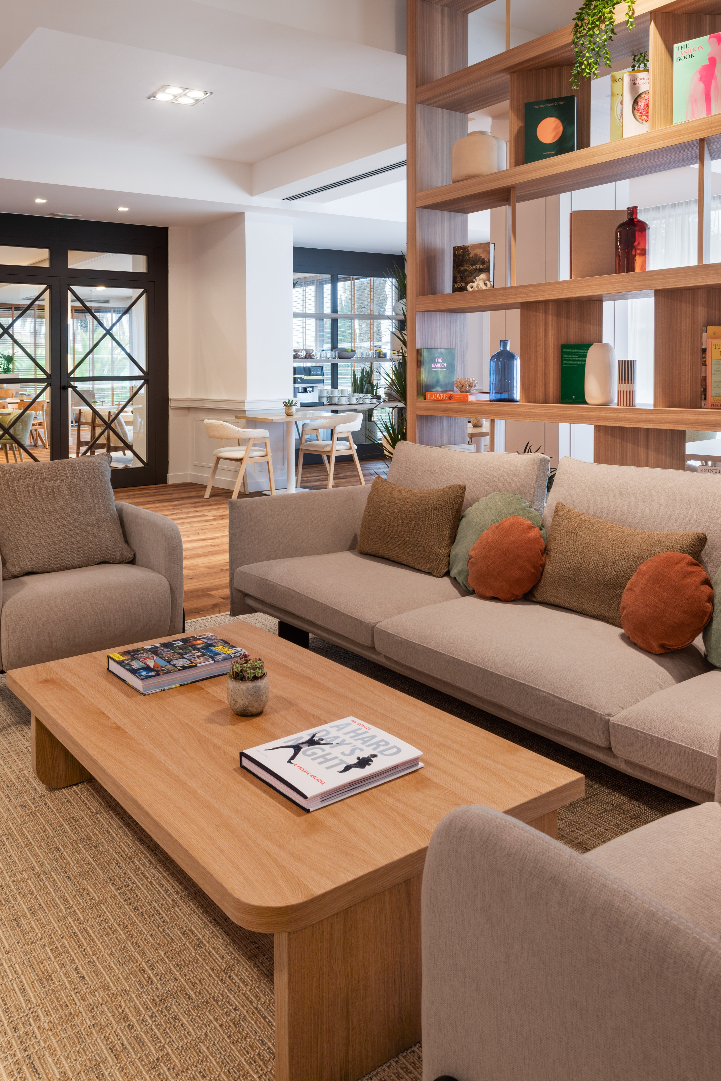 Modern hotel lounge with comfortable sofa, wooden coffee table, and stylish bookshelf.