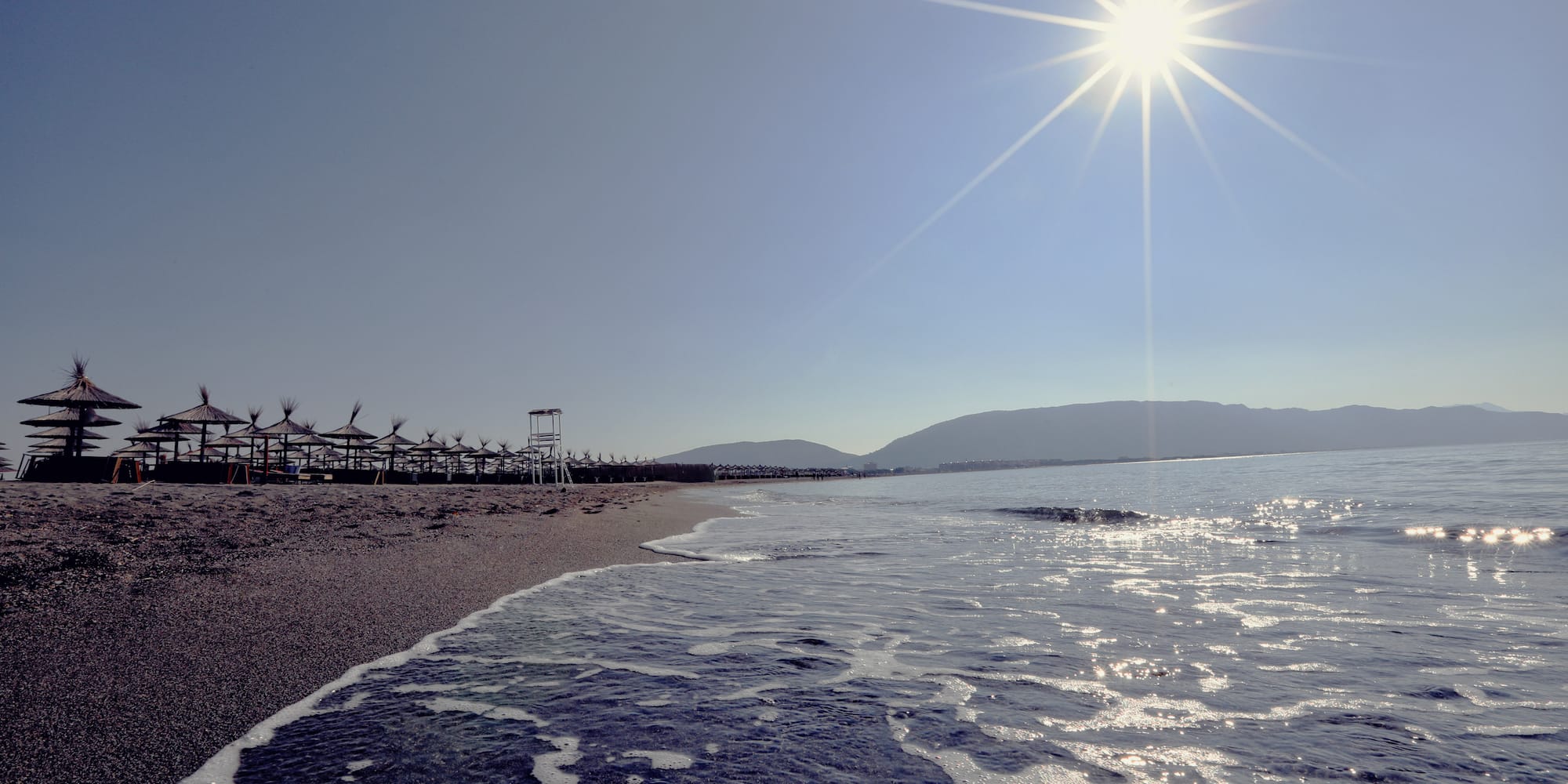 a beach with a body of water and a beach umbrellas