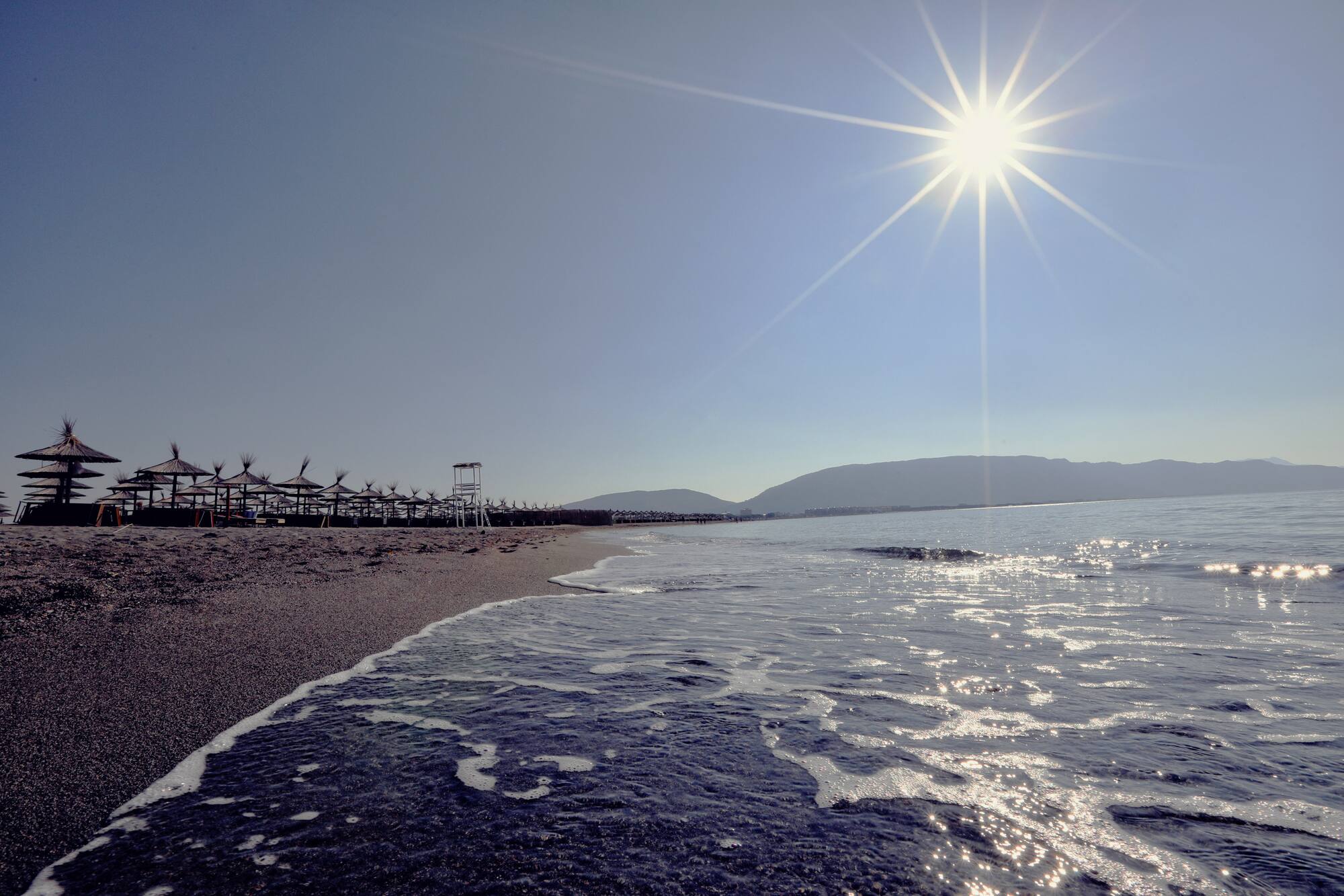 a beach with a body of water and a beach umbrellas