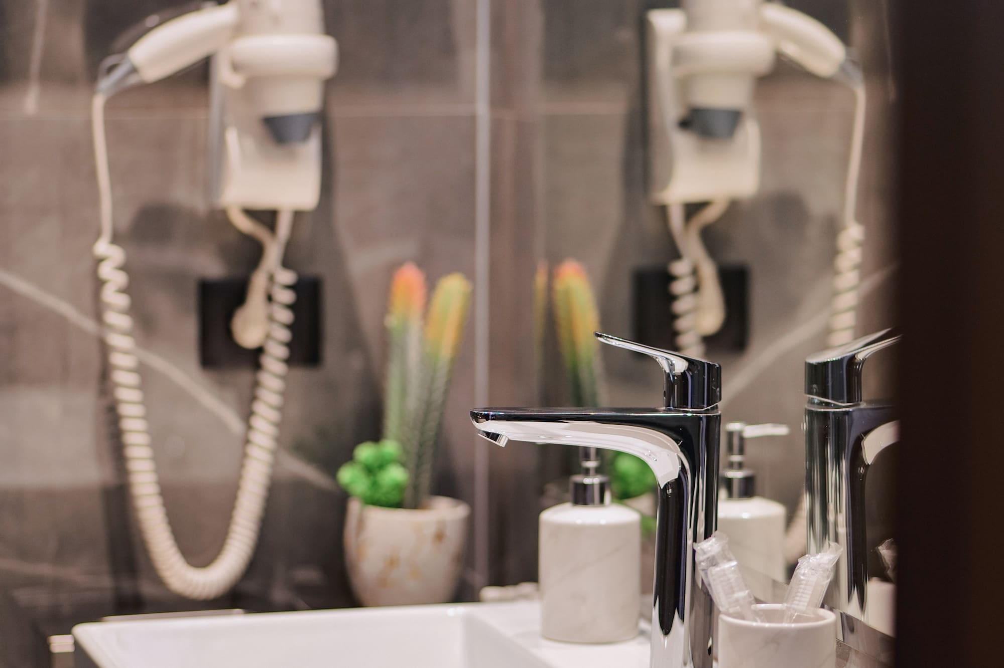 Modern bathroom vanity with white sink, chrome faucet, hairdryer, and plants.